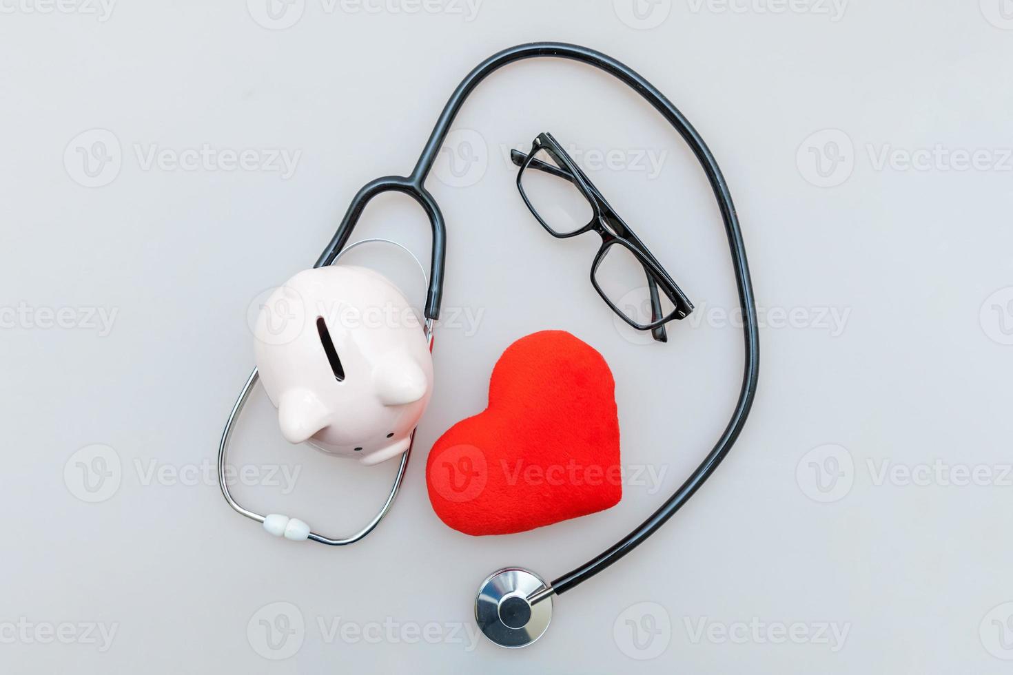 Medicine doctor equipment stethoscope or phonendoscope piggy bank glasses and red heart isolated on white background photo