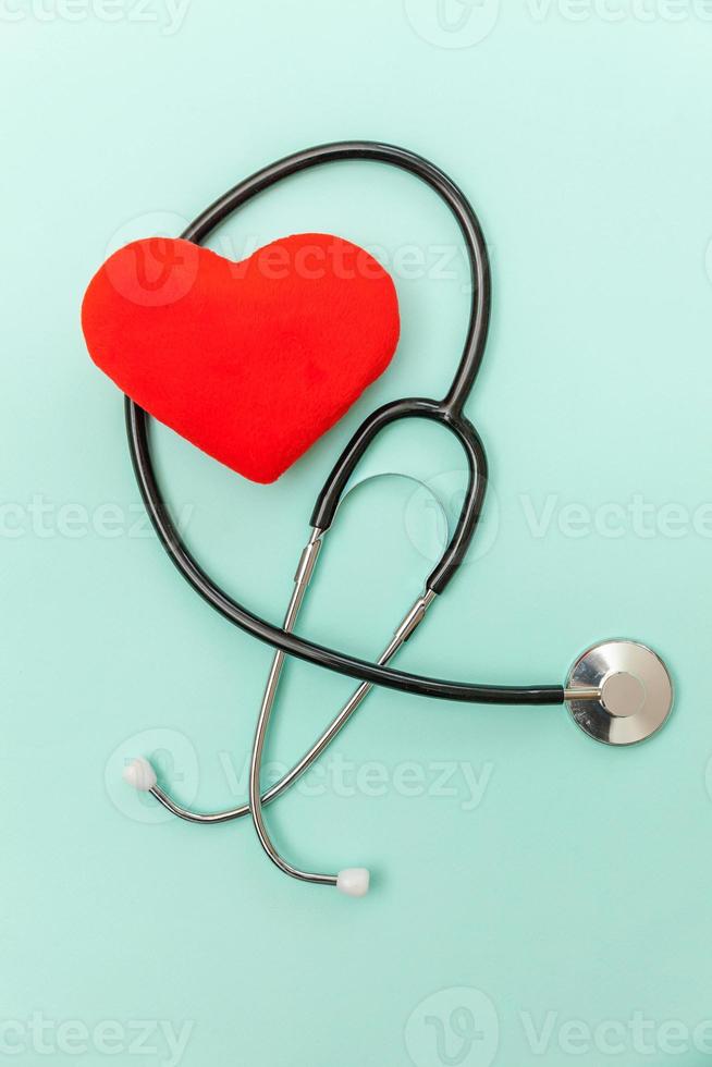 Medicine equipment stethoscope or phonendoscope and red heart isolated on trendy pastel blue background. Instrument device for doctor. Health care life insurance concept photo