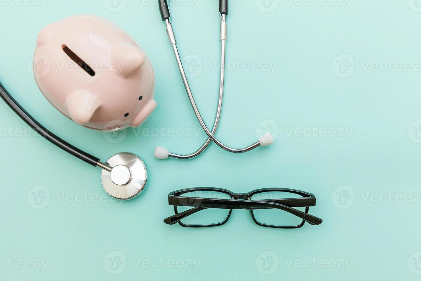 Medicine doctor equipment stethoscope or phonendoscope piggy bank glasses isolated on trendy pastel blue background photo