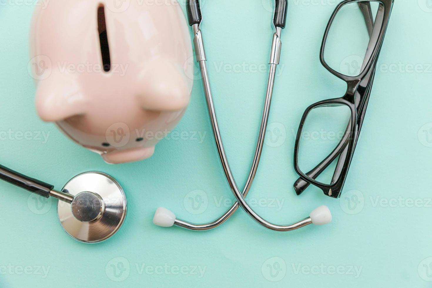 Medicine doctor equipment stethoscope or phonendoscope piggy bank glasses isolated on trendy pastel blue background photo