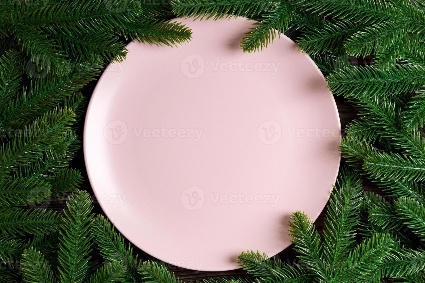 Top view holiday plate among green fir tree branches. Christmas dinner with copy space photo
