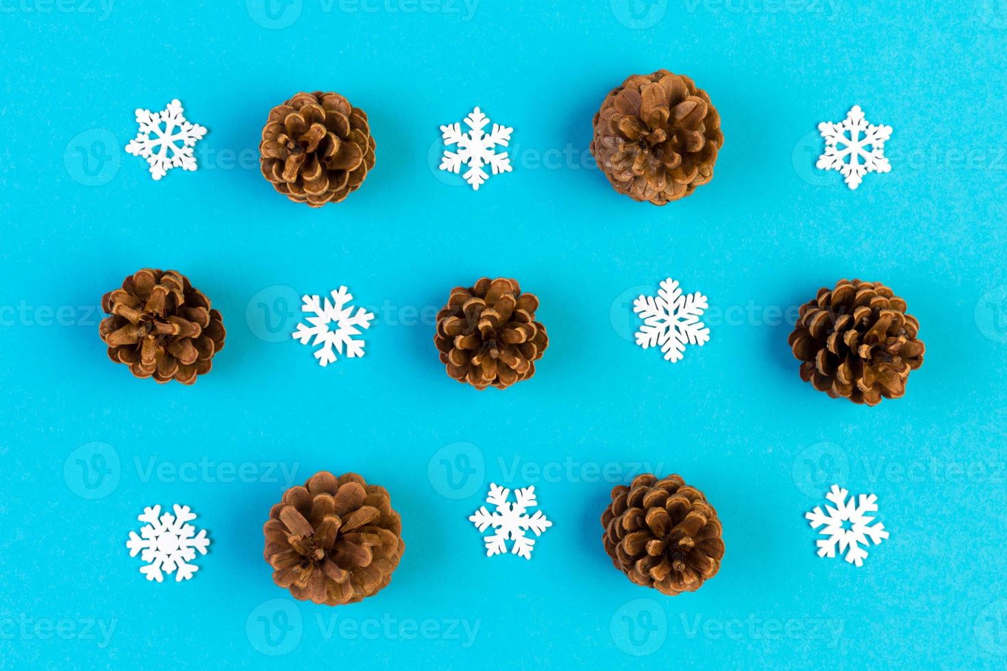Top view of holiday composition made of pine cones and white snowflakes on colorful background. Winter time and Christmas concept with copy space photo