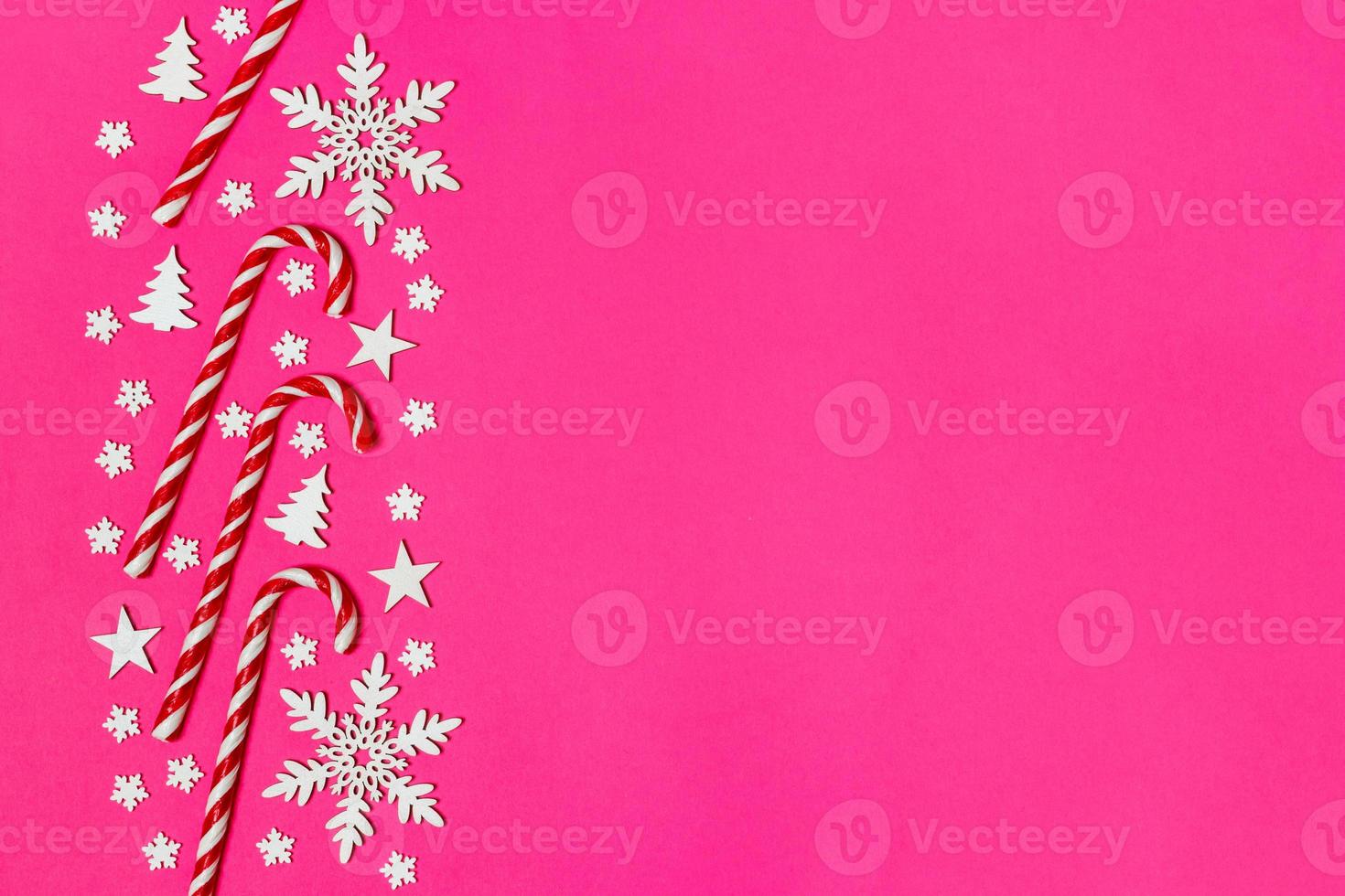 Christmas candy cane lied evenly in row on pink background with decorative snowflake and star. Flat lay and top view photo