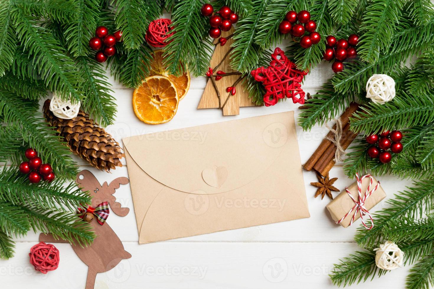 Top view of fir tree branches, envelope and festive decorative toys on wooden background. New Year time concept photo