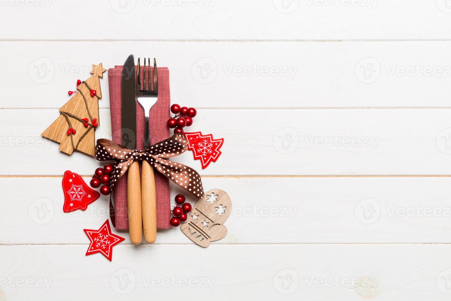 Top view of fork and knife tied up with ribbon on napkin on wooden background. Christmas decorations and New Year tree. Happy holiday concept with empty space for your design photo