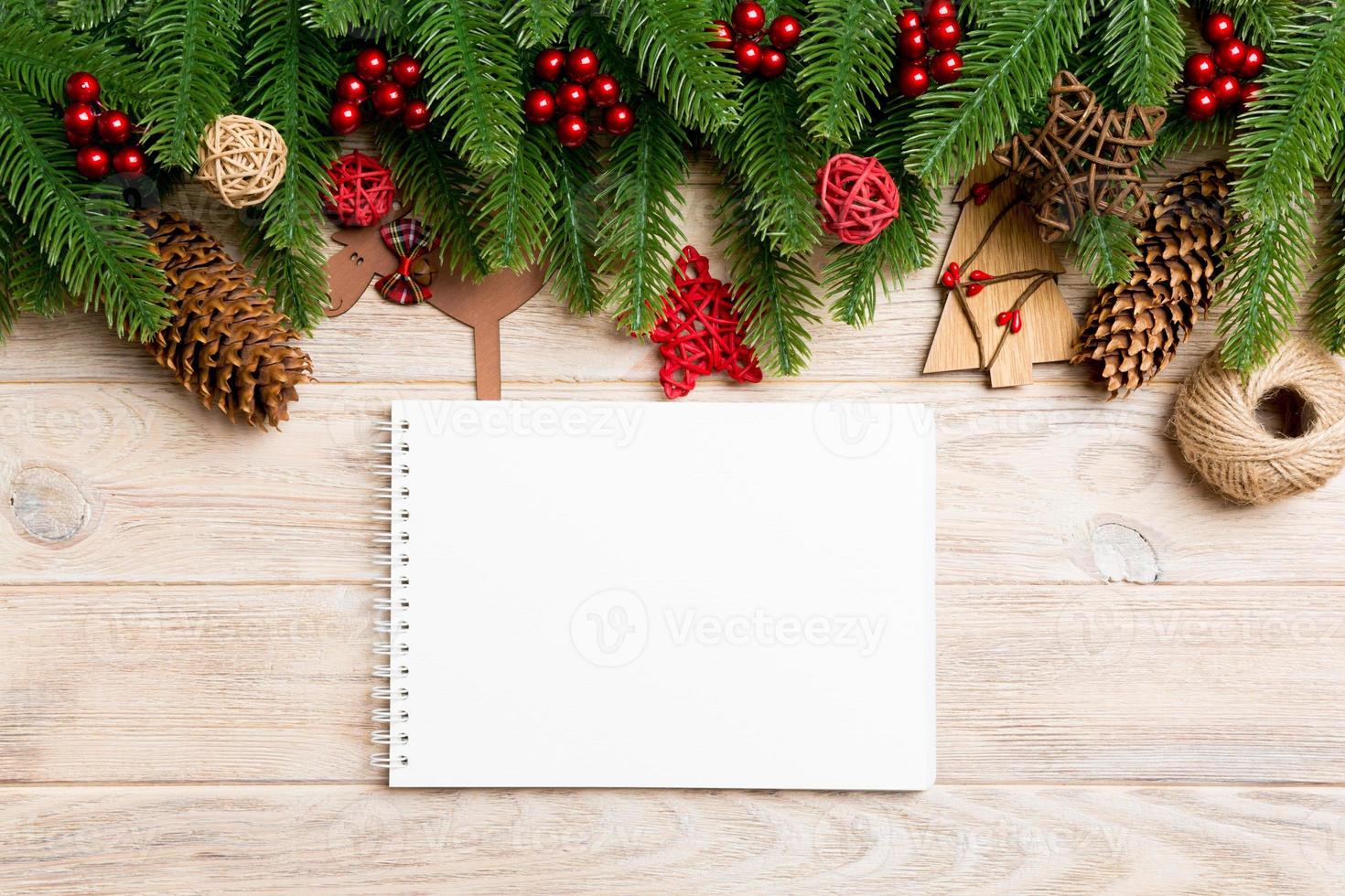 Top view of notebook, Christmas toys, decorations and fir tree branches on wooden background. New Year holiday concept photo