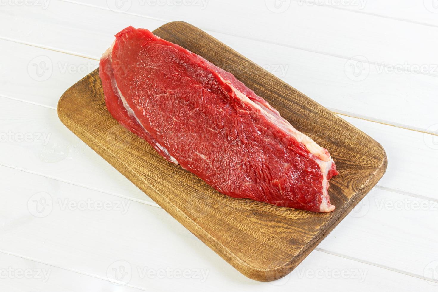 Fresh raw beef on a wooden cutting board on dark background, top view photo