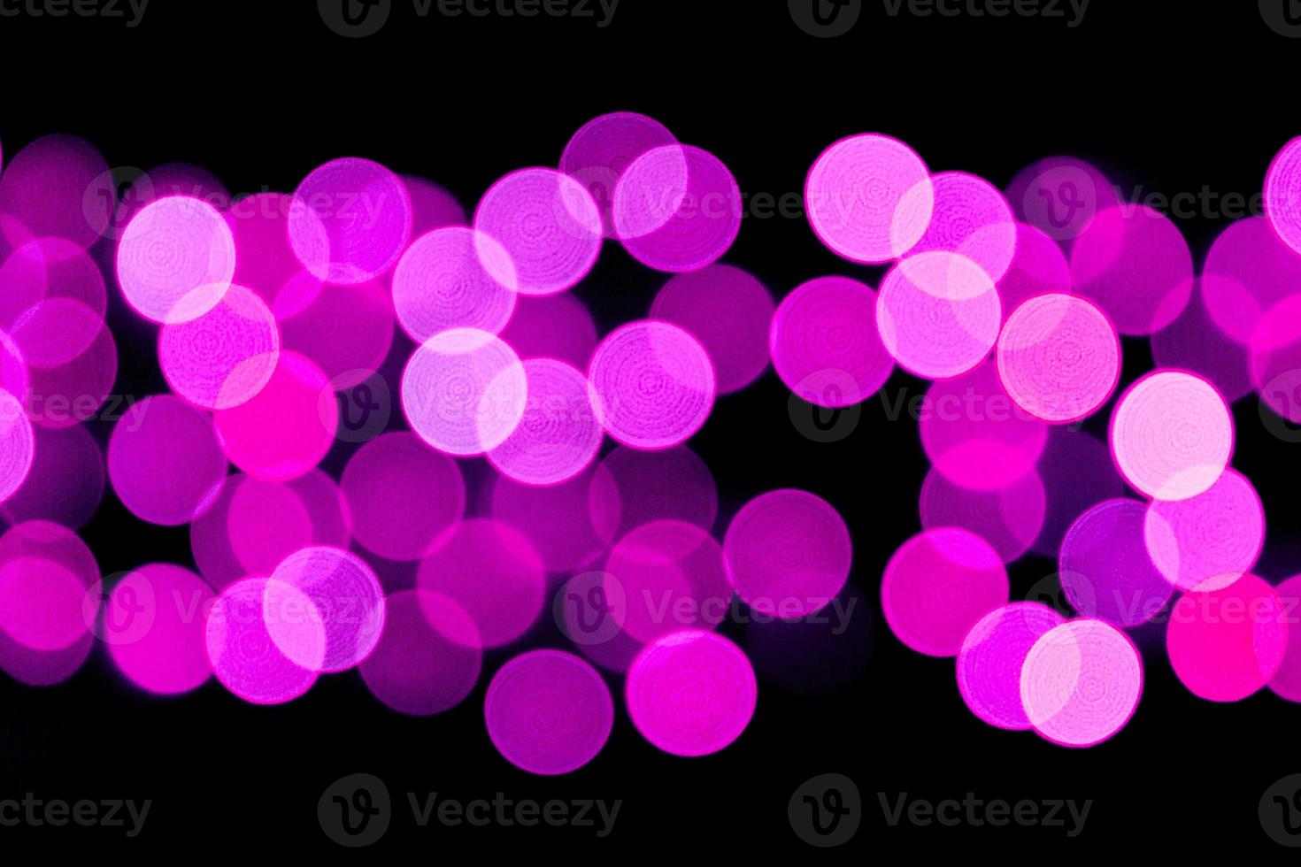 Unfocused abstract purple bokeh on black background. defocused and blurred many round light photo