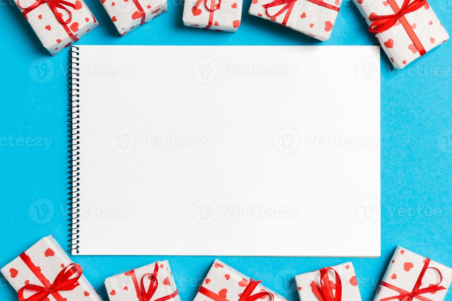 Top view of notebook surrounded with gift boxes on colorful background. Valentine's Day concept photo