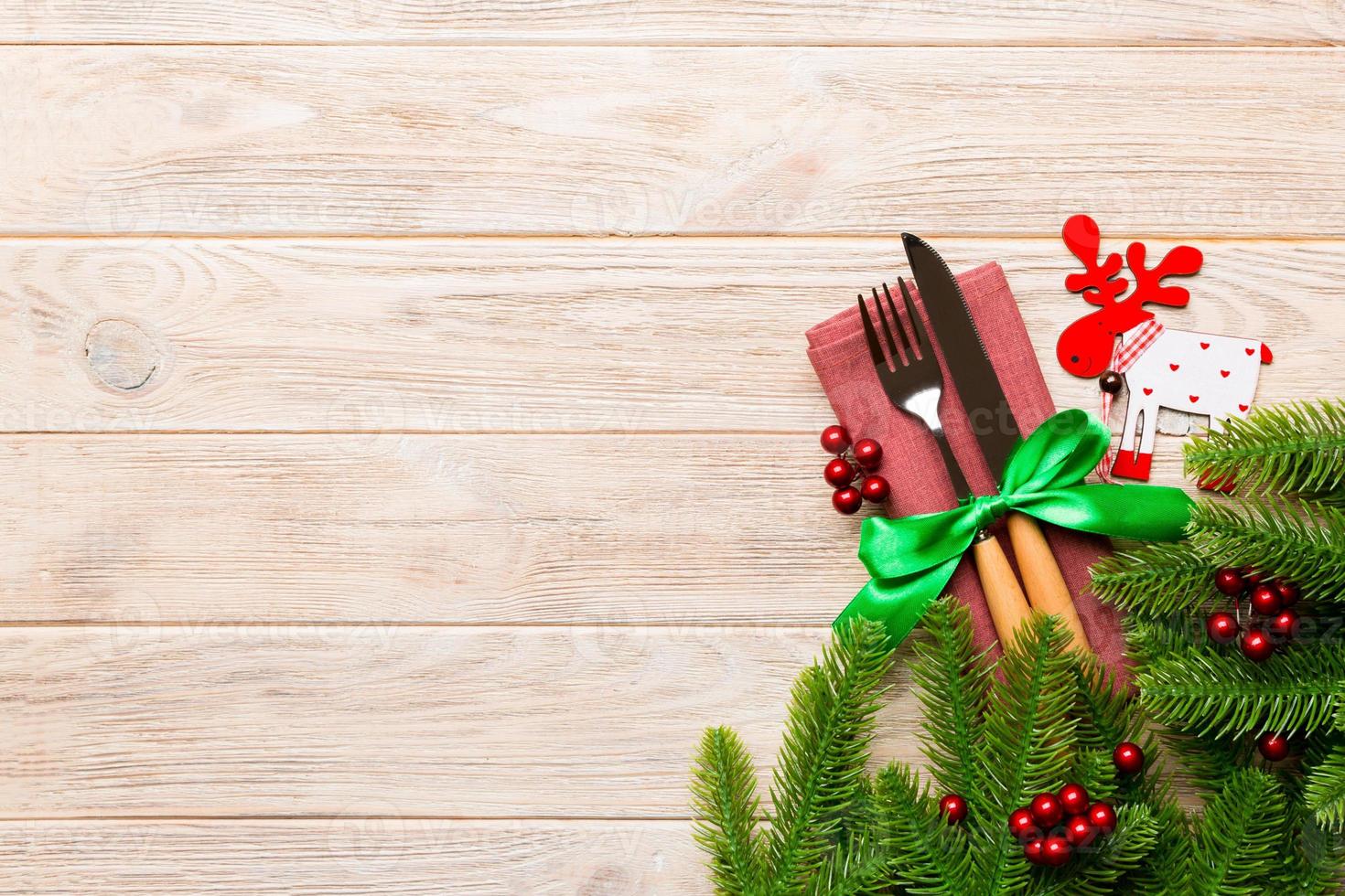 Top view of flatware tied up with ribbon on napkin on wooden background. Christmas decorations and reindeer with empty space for your design. New Year holiday concept photo