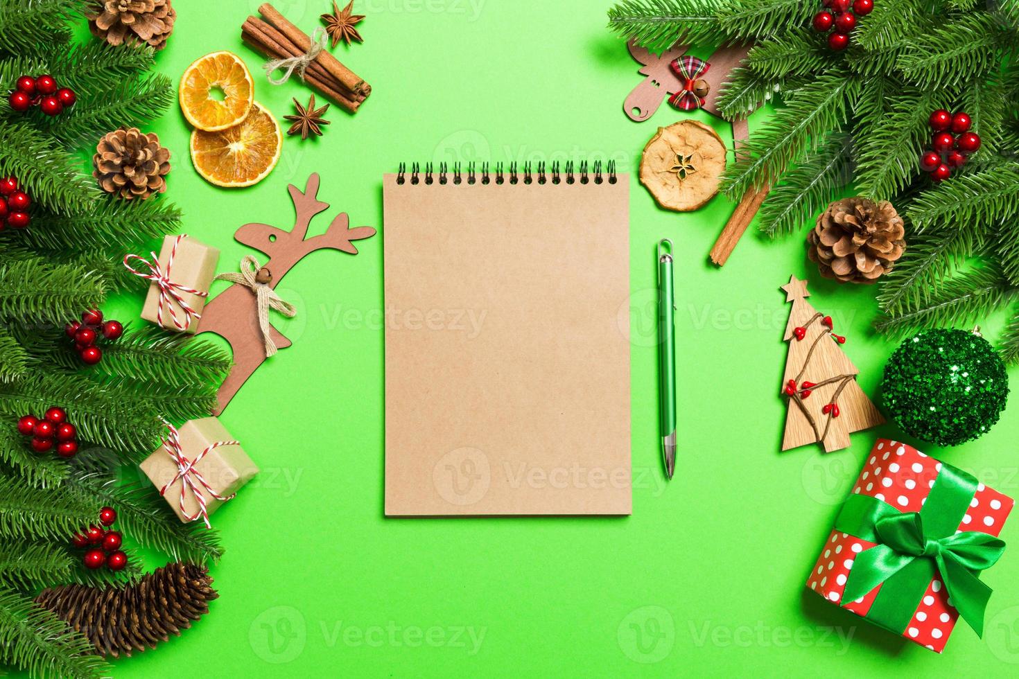 Top view of notebook on green background made of Christmas decorations. New Year time concept photo