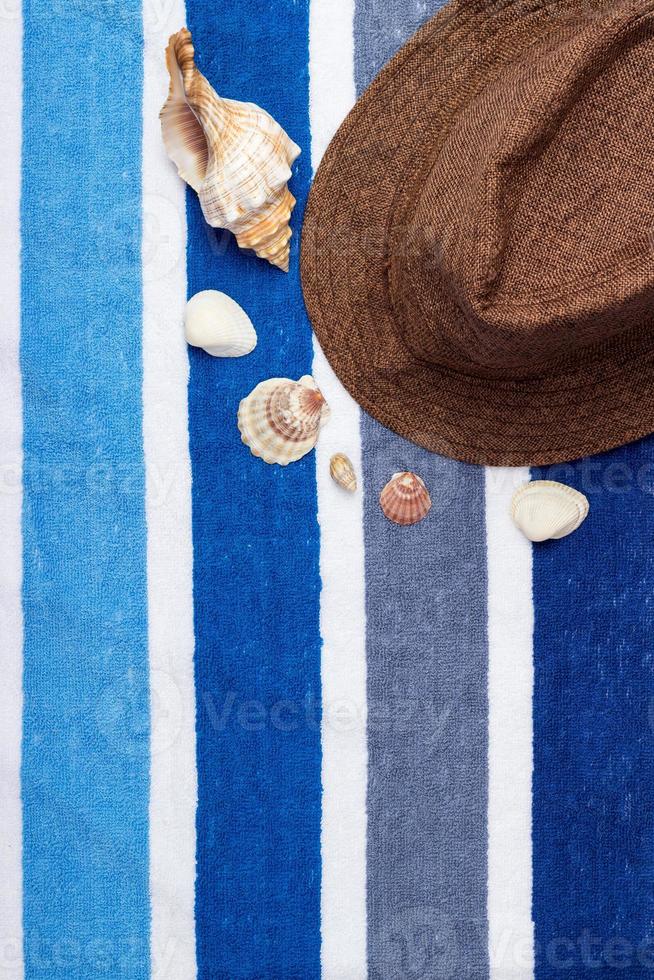 A summer holiday composition on a beach towel with seashells and a hat. photo