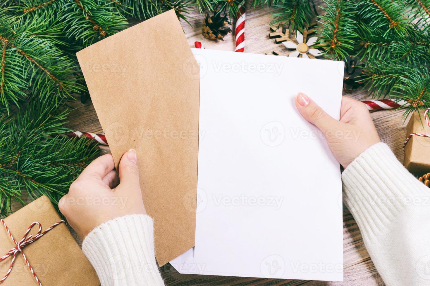 manos con cuaderno y un sobre para carta. una niña está lista para enviar una carta con deseos a santa claus. tonificado foto