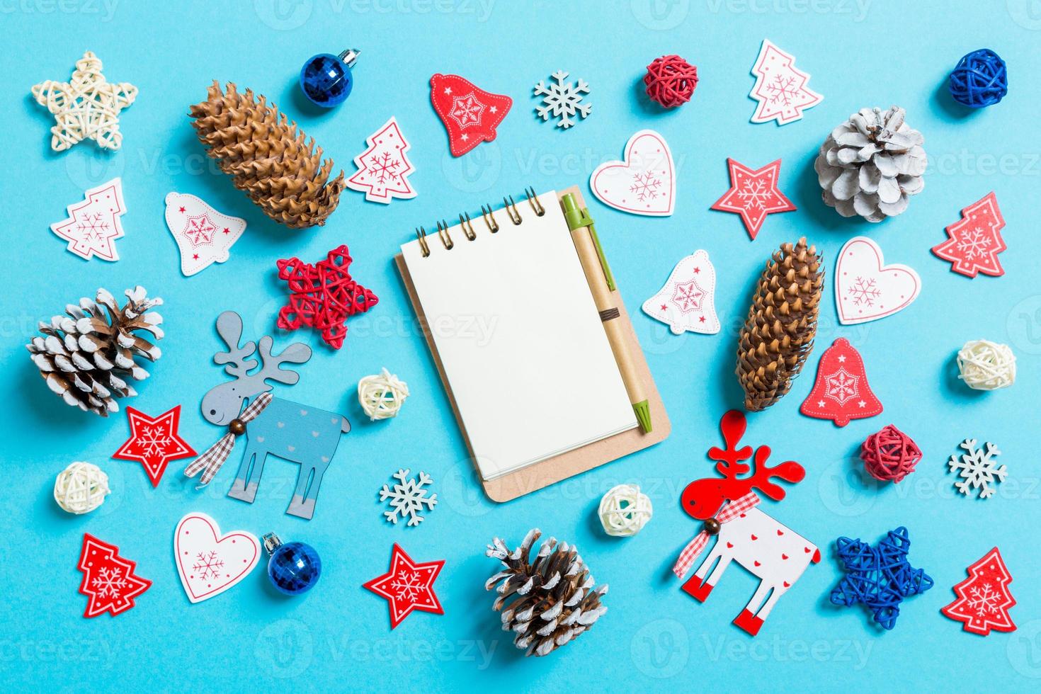 Top view of notebook surrounded with New Year toys and decorations on blue background. Christmas time concept photo