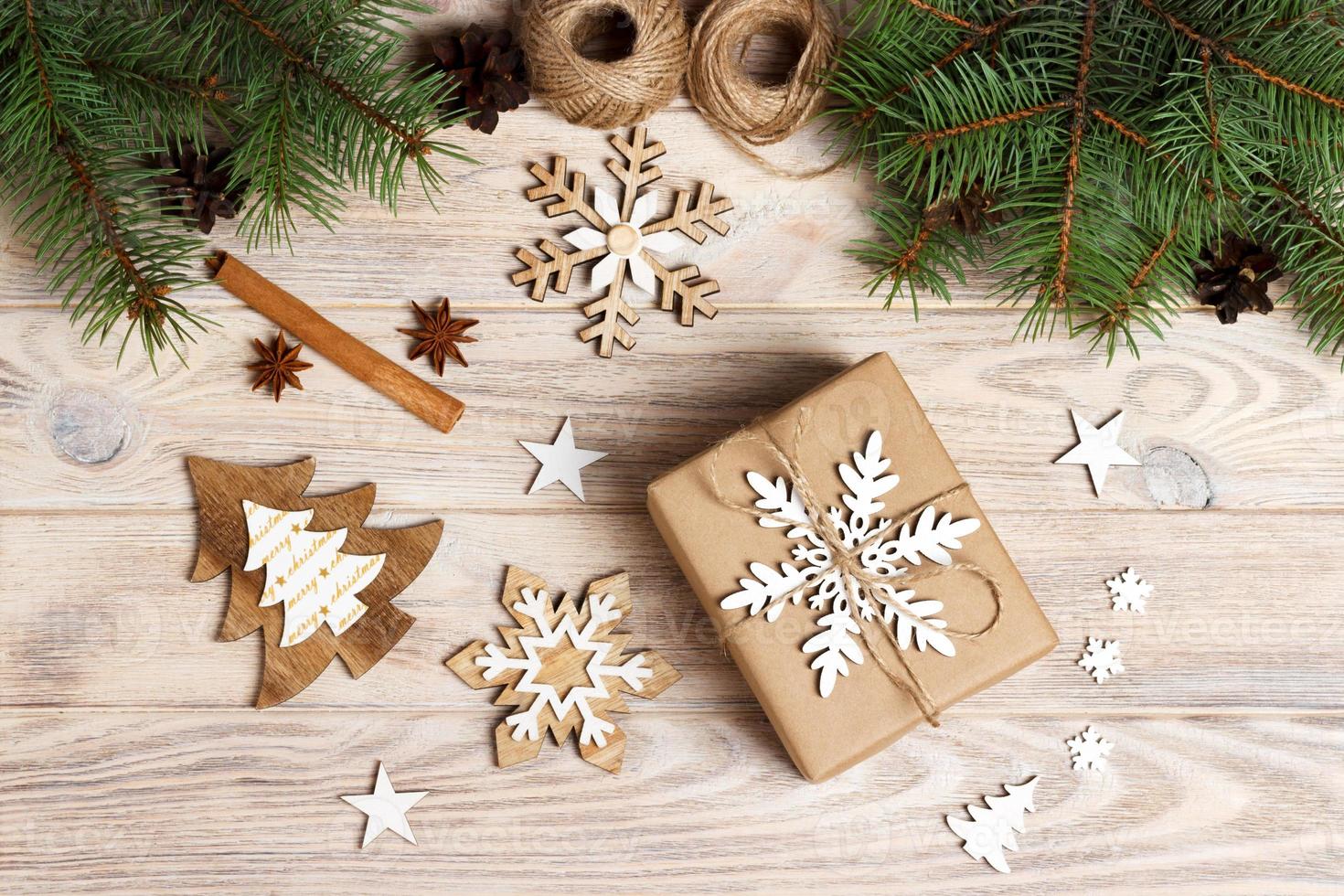 gift box in craft paper with Christmas decoration, twine rope, concept background, top view on wood table surface. Christmas ornaments and presents border with snowflakes and stars photo