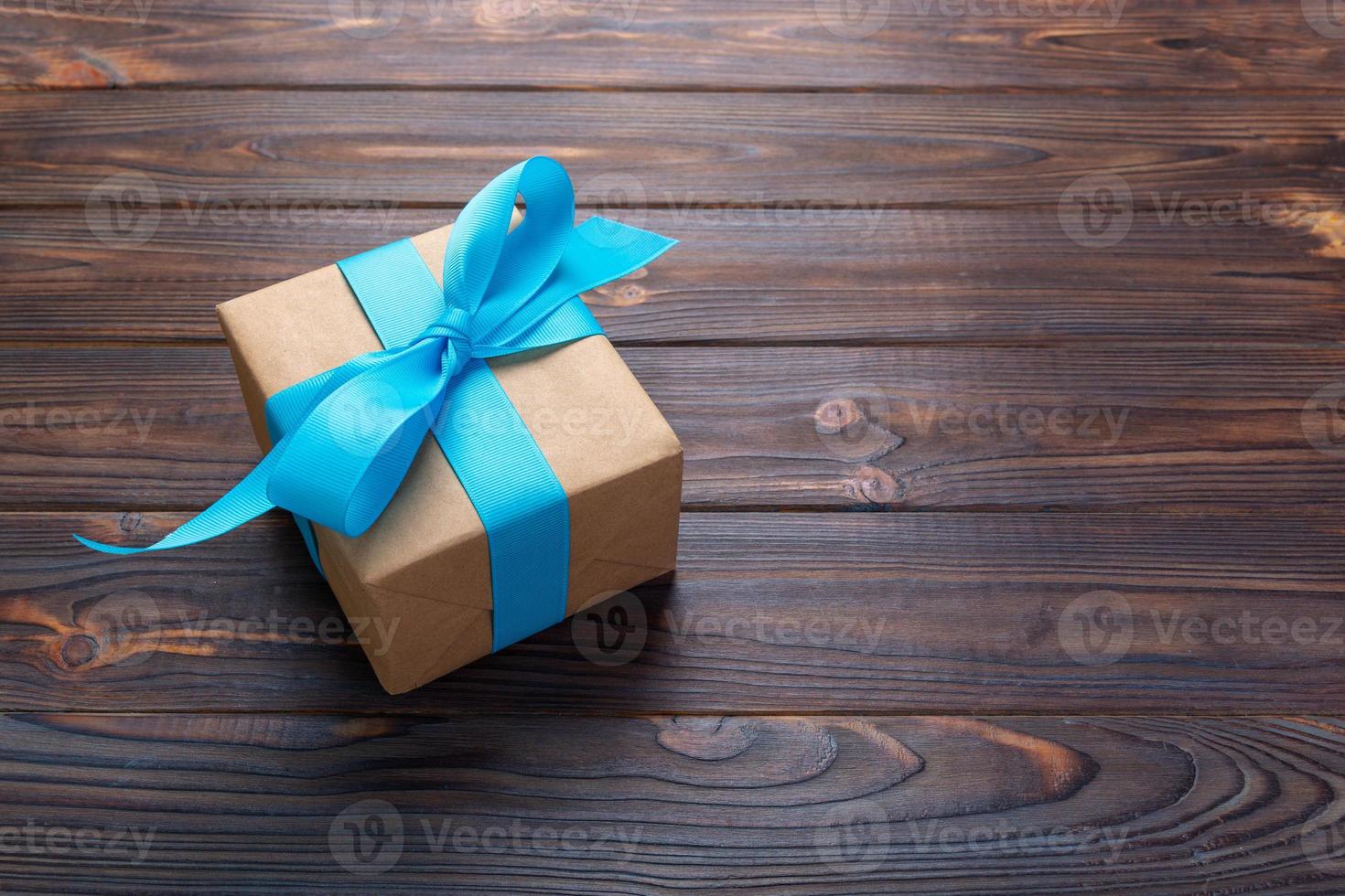 paper gift box with blue ribbon on dark wood background. top view with copy space photo