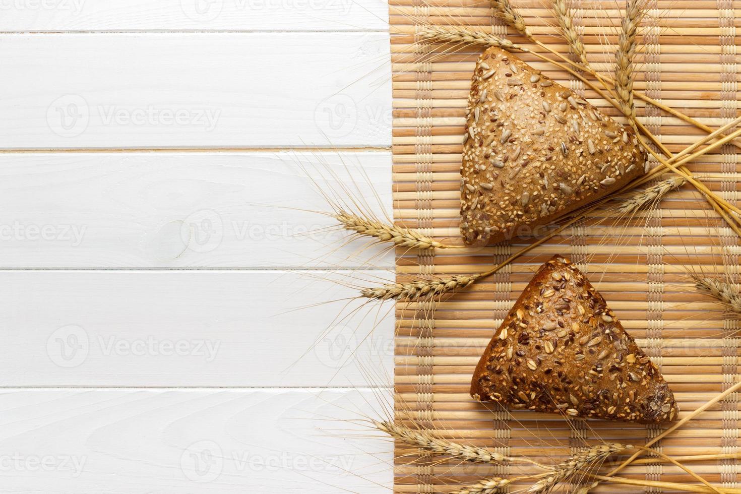 Several small multi grain triangular shaped bread sprinkled with whole sunflower seeds, flax and sesame seeds and wheat and barley spikes photo