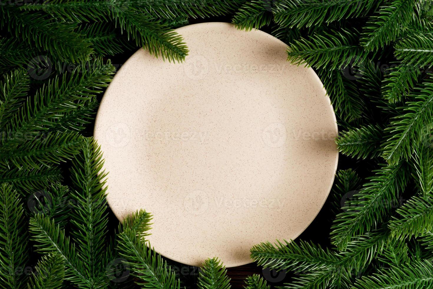 Top view of round festive plate on fir tree background. Christmas dish concept with empty space for your design photo