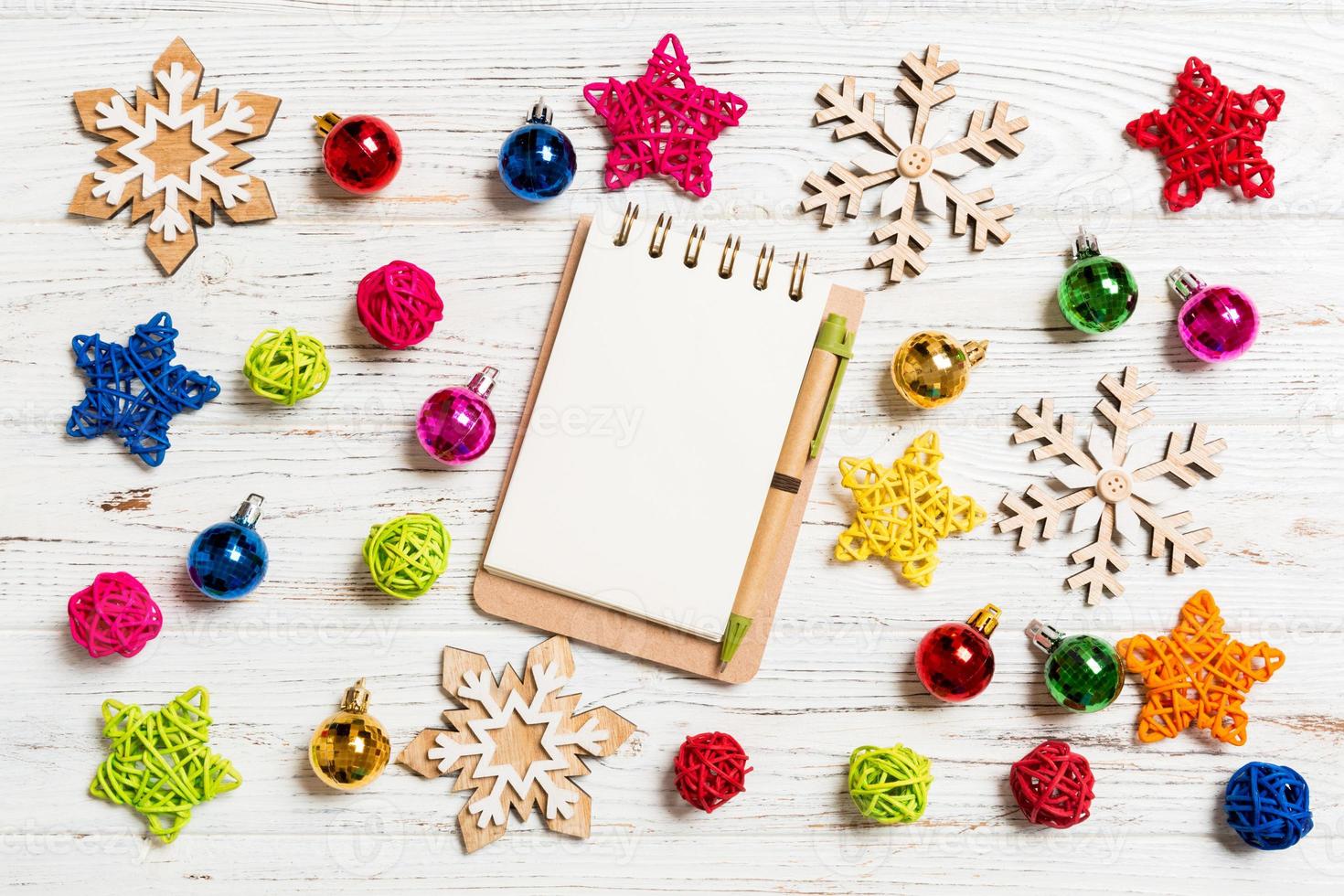 Top view of notebook on wooden background made of Christmas decorations. New Year concept photo