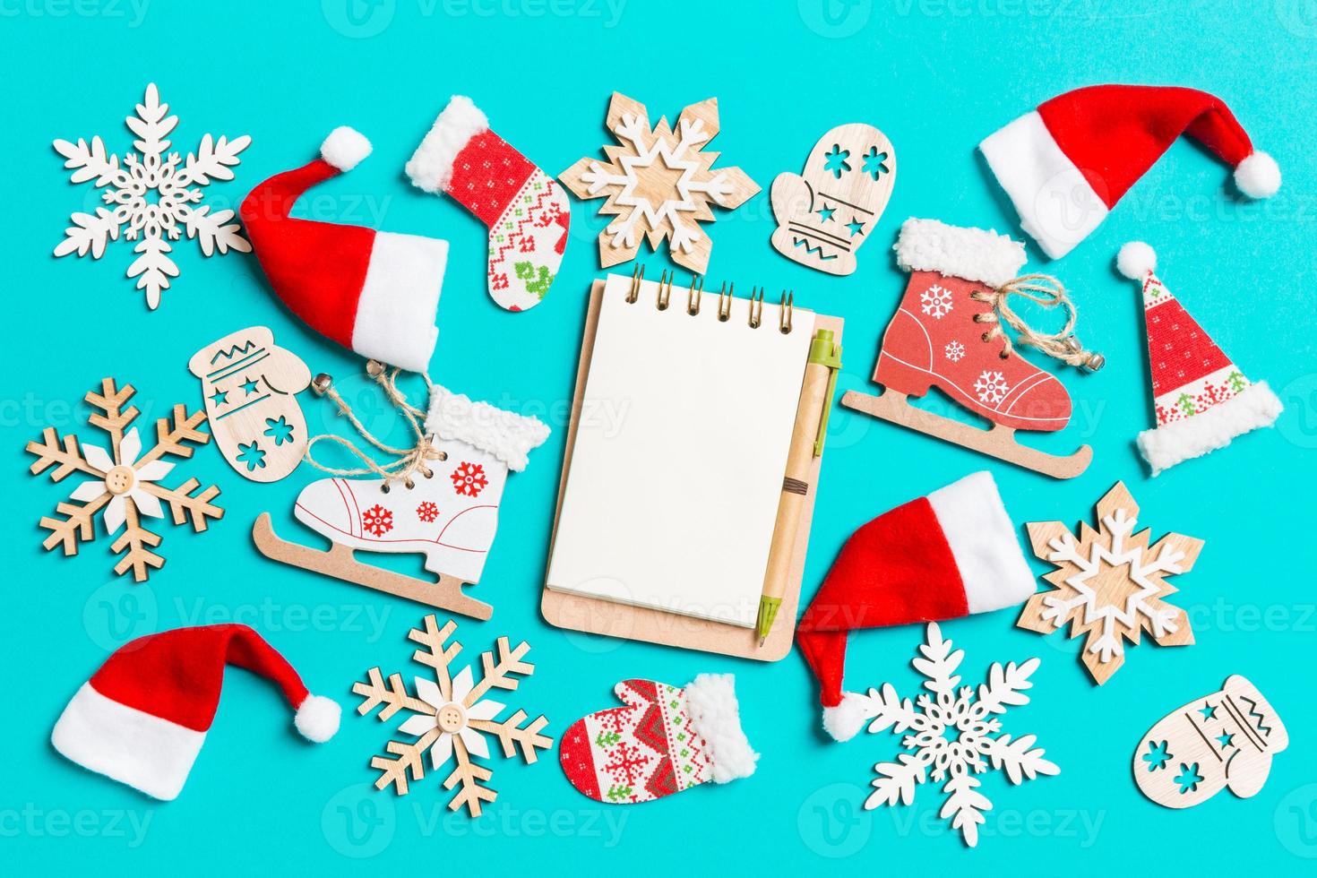 Top view of notebook with Christmas decorations and Santa hats on blue background. Happy holiday concept photo