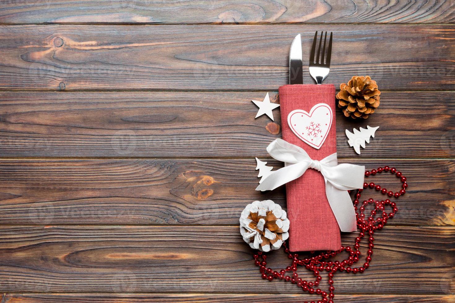 Top view of New Year dinner on wooden background. Festive cutlery on napkin with christmas decorations and toys. Family holiday concept with copy space photo