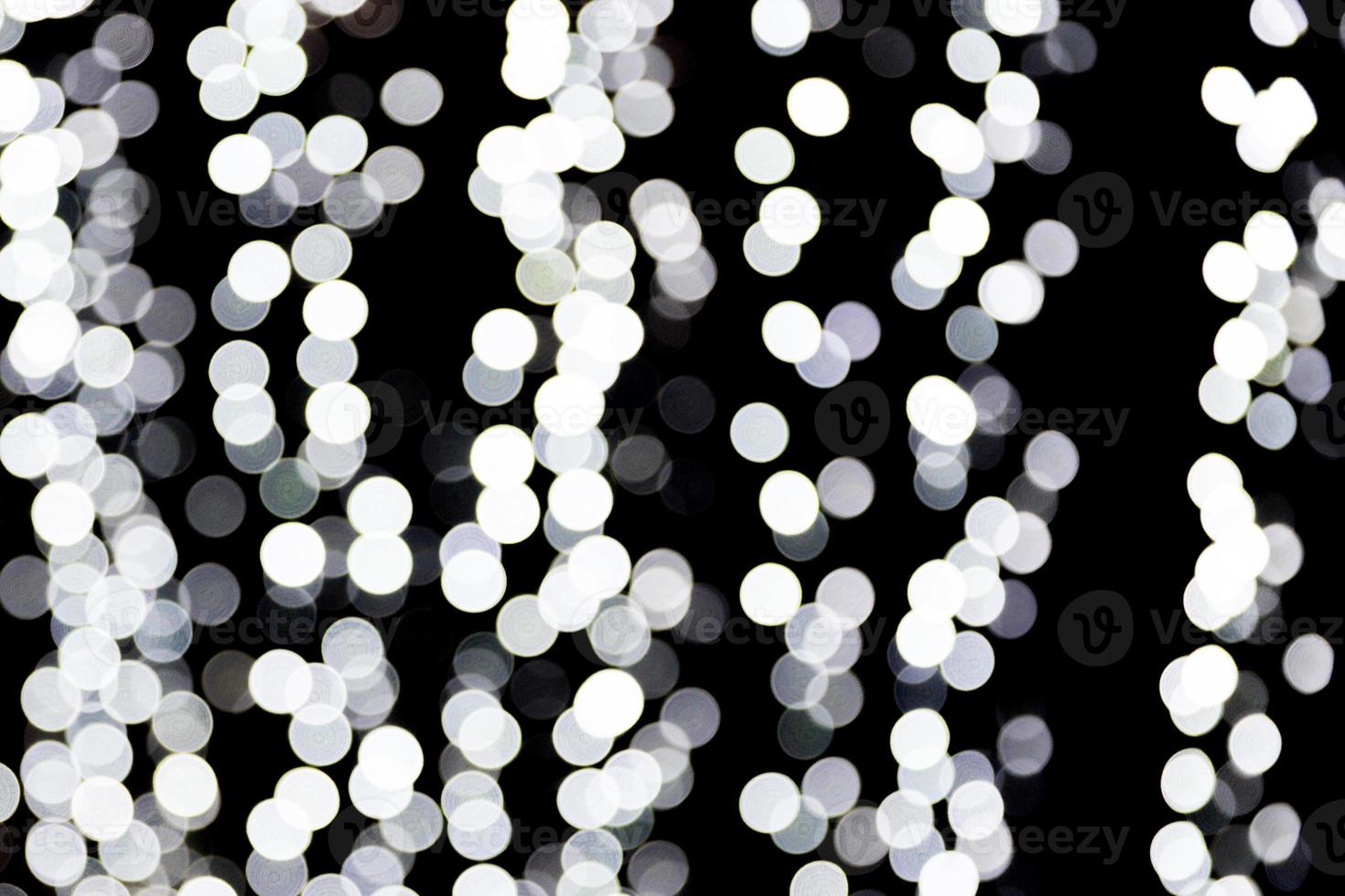 Bokeh blanco abstracto desenfocado sobre fondo negro. desenfocado y borroso muchas luces redondas foto