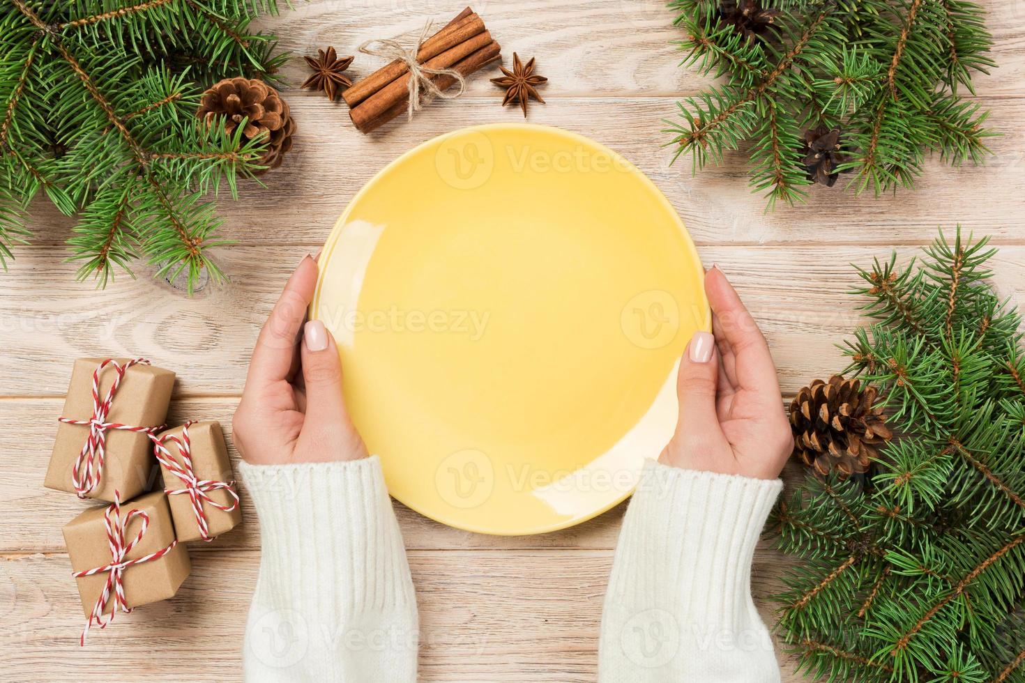 girl hand hold Top view. Empty yellow plate on wooden background with christmas decoration. New Year concept photo