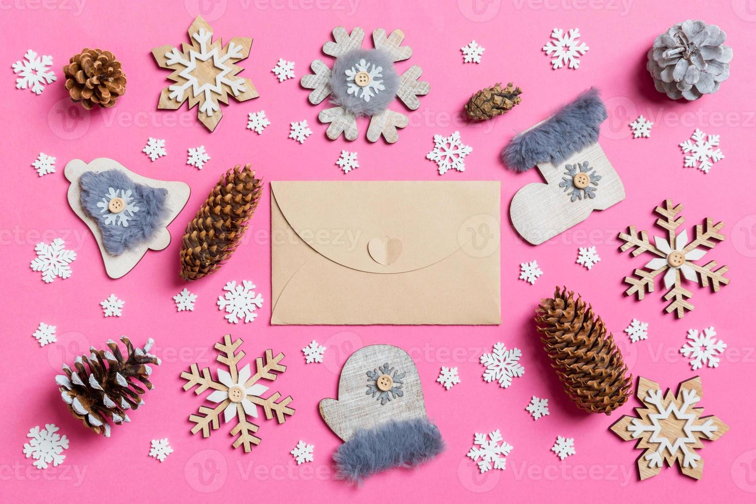 Top view of craft envelope, holiday toys and decorations on pink Christmas background. New Year time concept photo