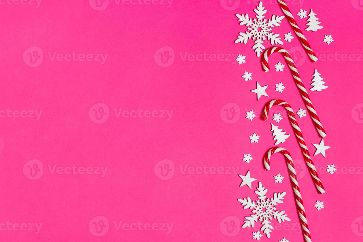 Christmas candy cane lied evenly in row on pink background with decorative snowflake and star. Flat lay and top view photo