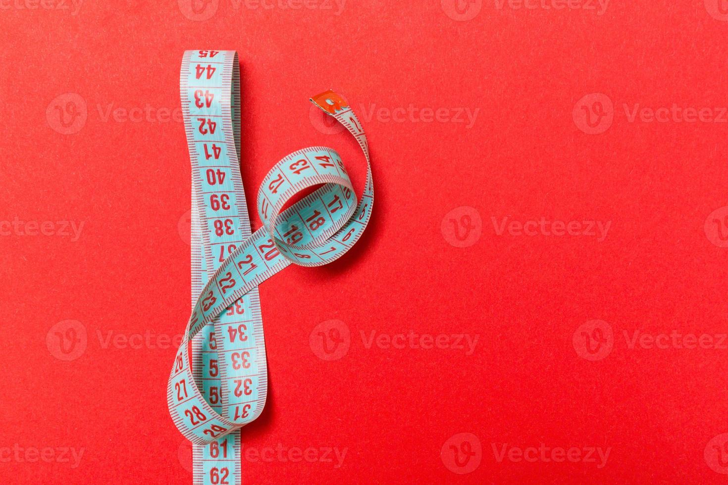 Top view of measuring tape on red background. Tailor and slim waist concept with emty space for your idea photo