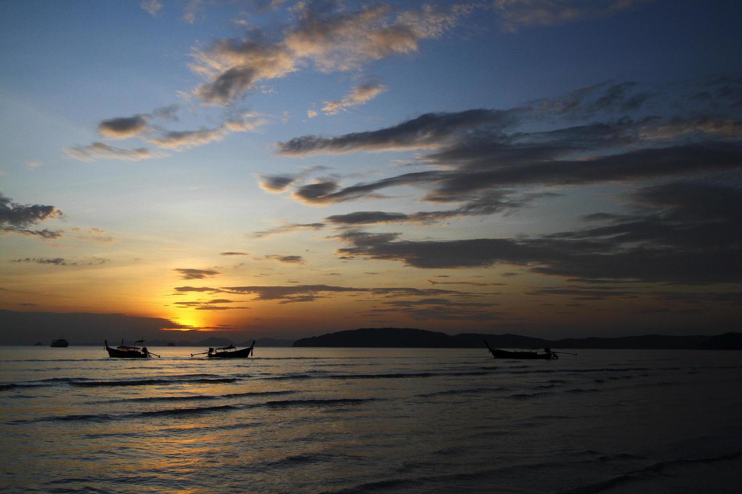 Silhouette of ship and long tail boat on sea or ocean with blue sky and cloud at sunset, sunrise or twilight time at Krabi, Thailand. Beauty in nature with wave and Transportation concept photo