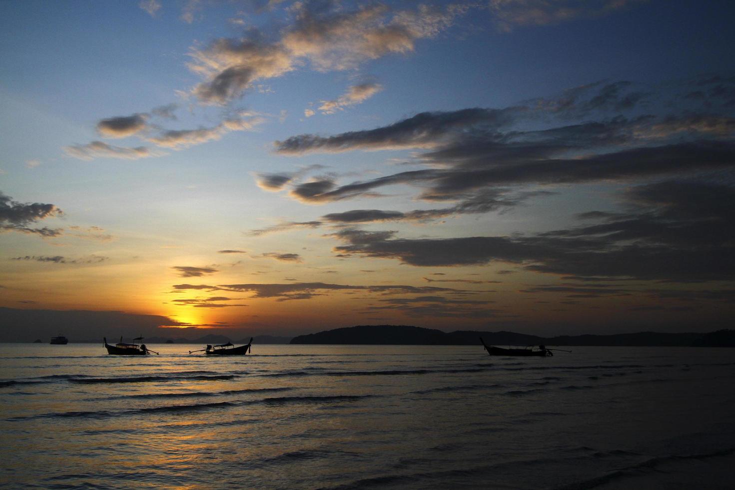 silueta de barco y bote de cola larga en el mar o el océano con cielo azul y nubes al atardecer, amanecer o crepúsculo en krabi, tailandia. belleza en la naturaleza con concepto de onda y transporte foto