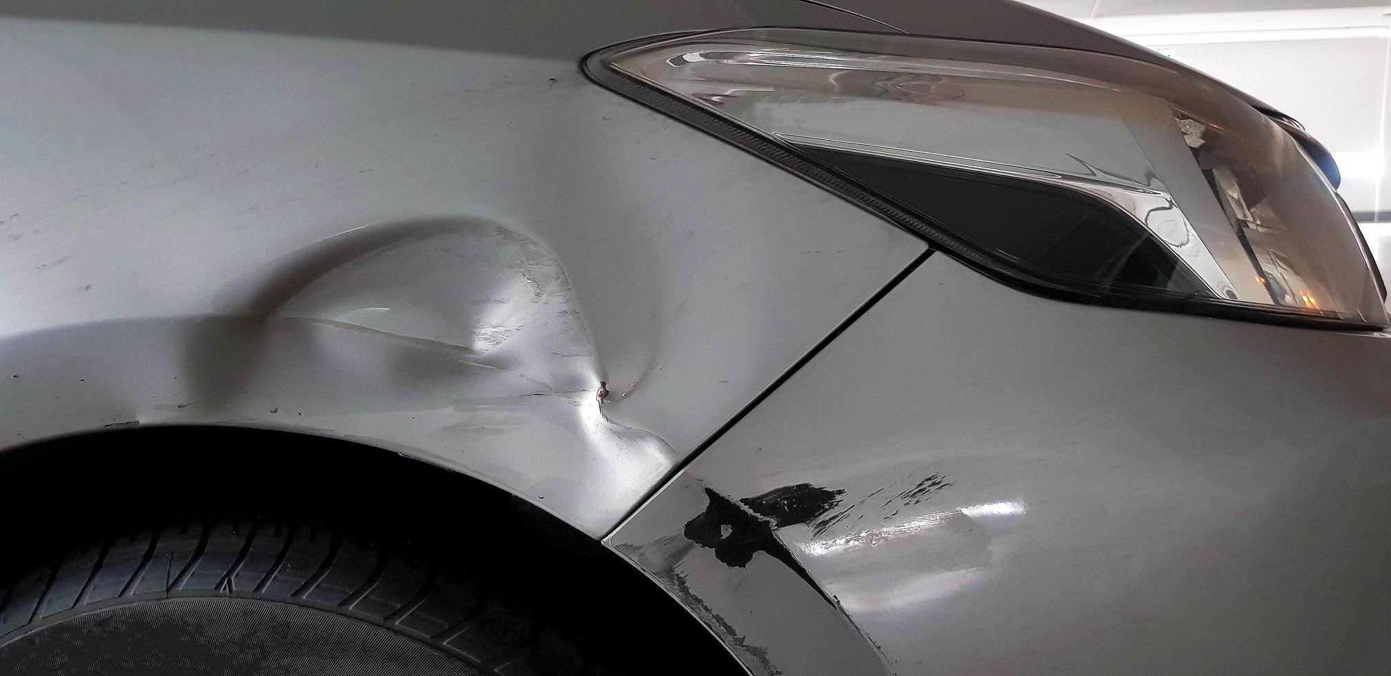 arañazos en coche gris, gris o bronce después de un accidente. dañado en el parachoques delantero derecho cerca de la rueda. concepto de seguro y lesiones del vehículo foto