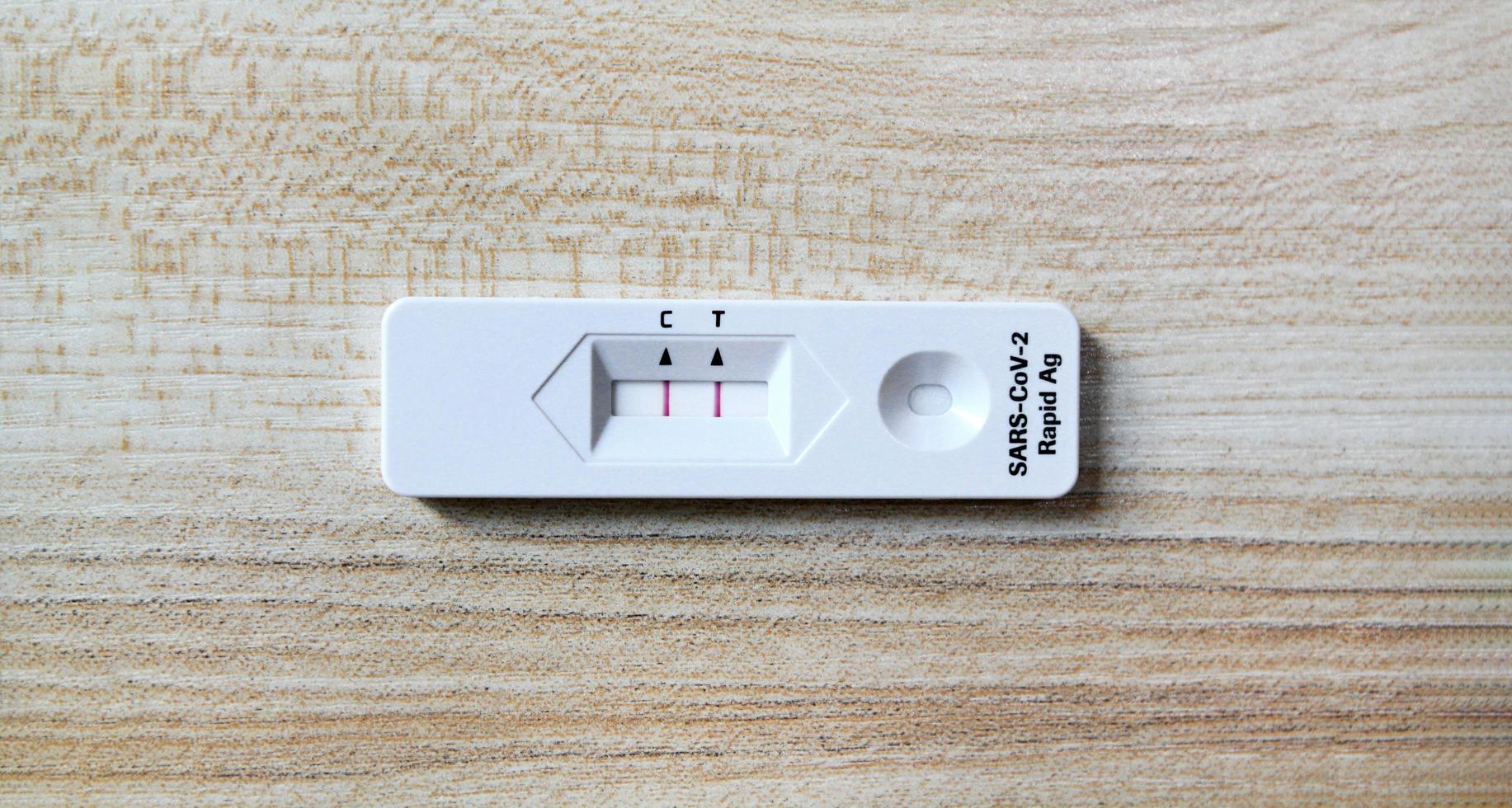 resultado positivo de la prueba mediante el uso de la prueba rápida de antígeno para covid-19 sobre fondo de madera con espacio de copia. control saludable, infección por el virus de la corona, pandemia infecciosa y médica. comprobación inicial de síntomas. foto