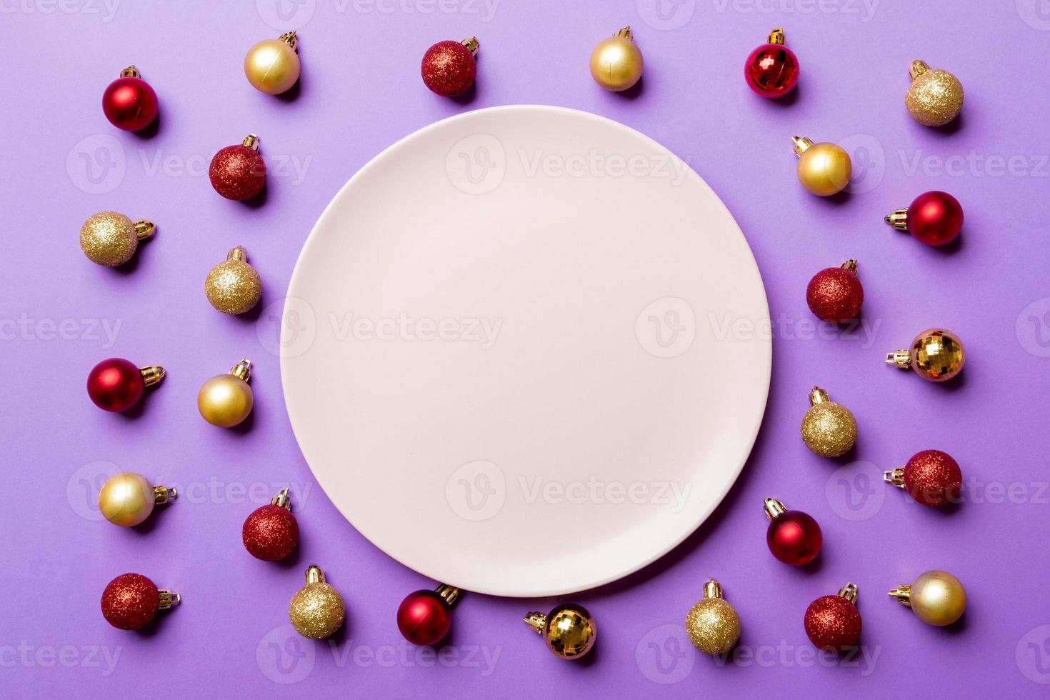 Top view of festive plate with red and golden baubles on colorful background. Christmas decorations and toys. New Year advent concept photo