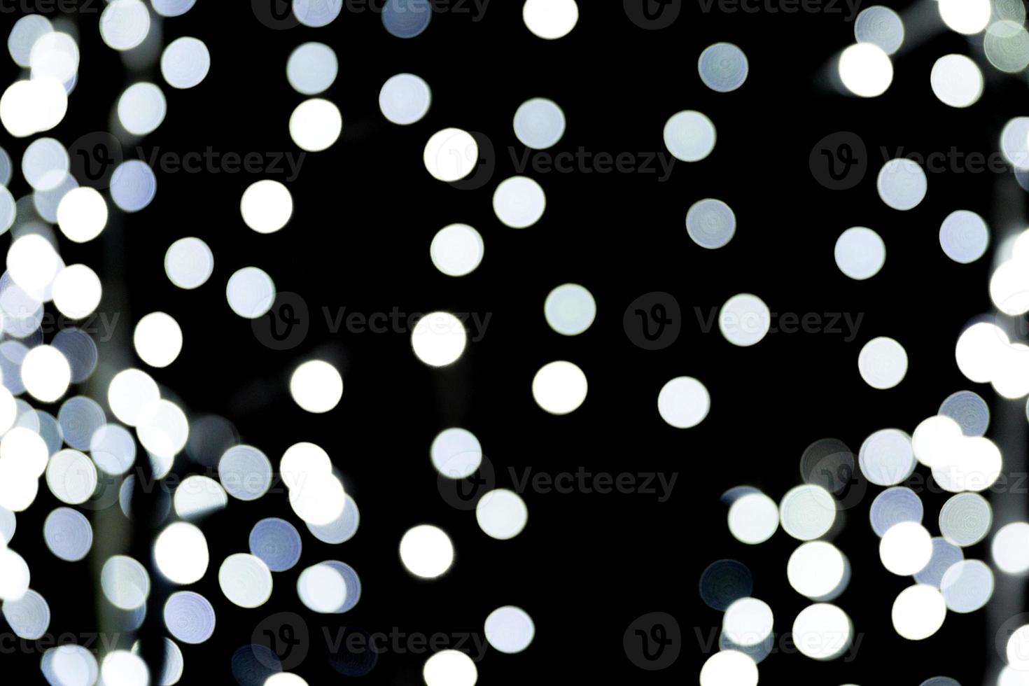 Bokeh abstracto de luces de la ciudad blanca sobre fondo negro. desenfocado y borroso muchas luces redondas foto