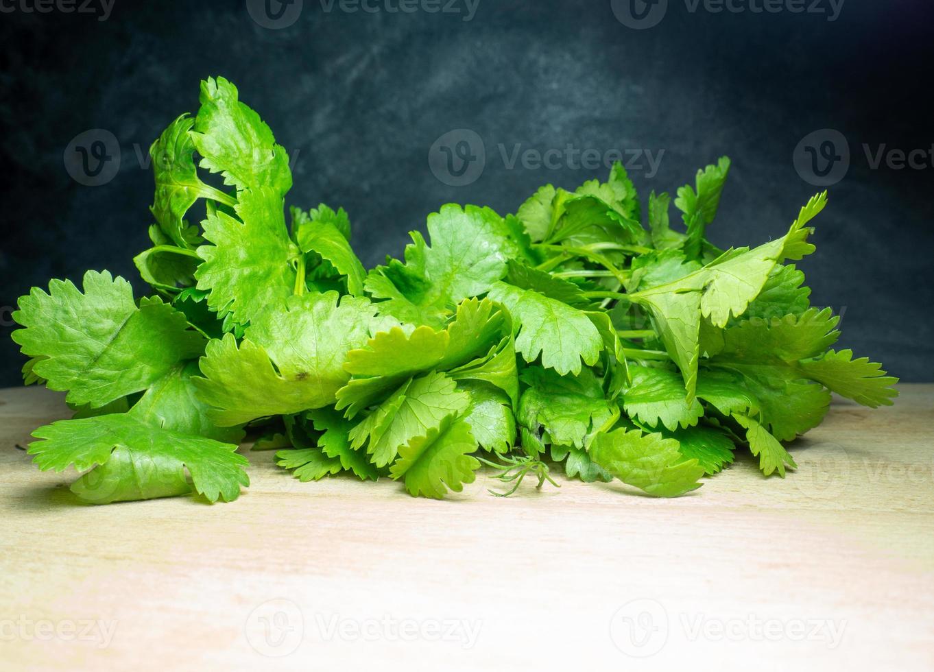 A bunch of coriander on a cutting board. Useful product. Greens on the kitchen table. Vegetarian lunch ingredient. Lots of cilantro stalks. photo