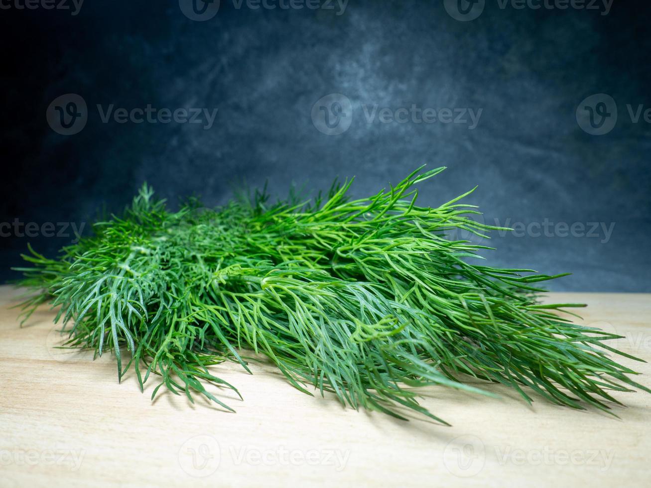 A bunch of dill on a cutting board. Useful product. Greens on the kitchen table. Vegetarian lunch ingredient. photo