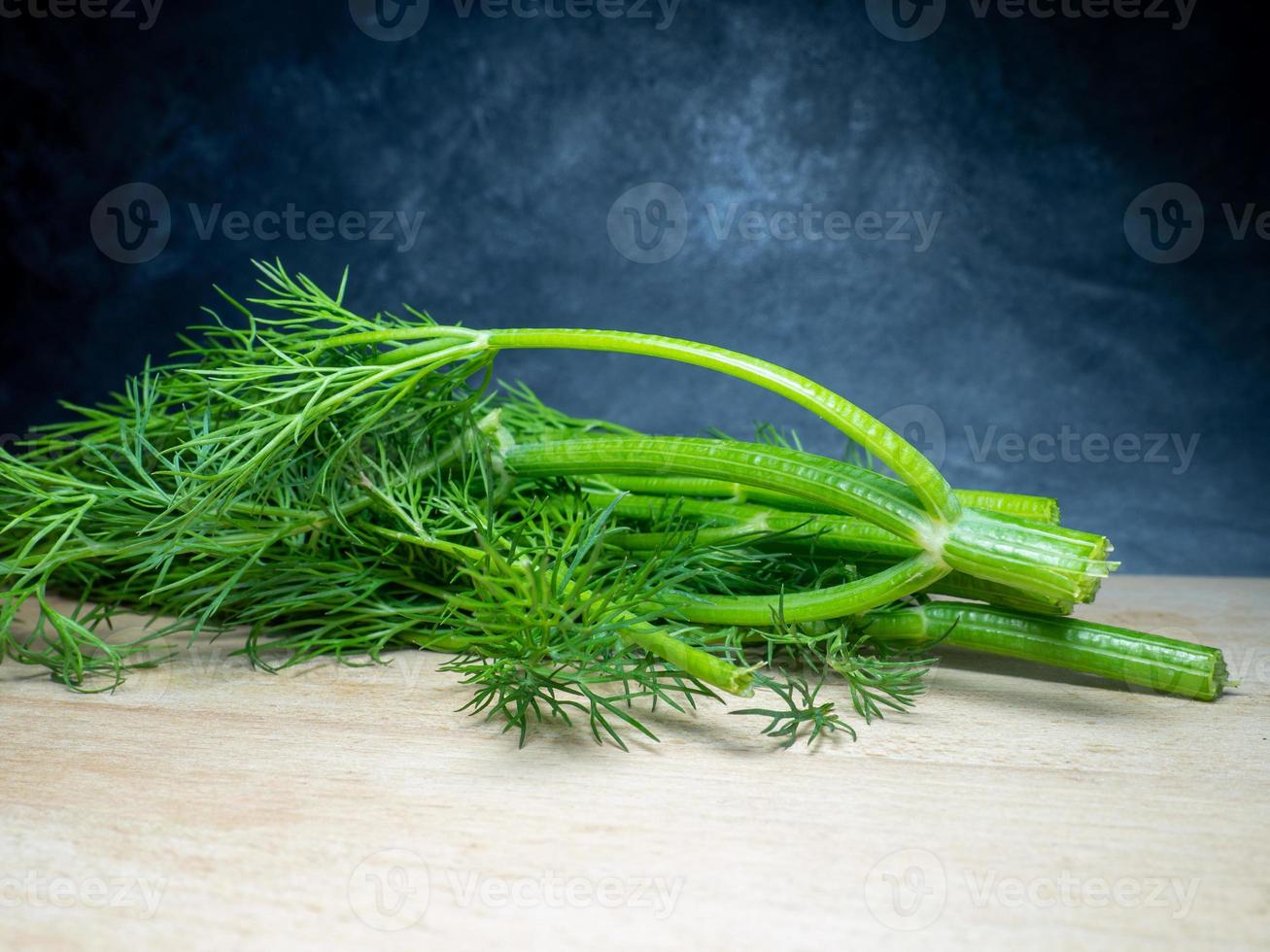 A bunch of dill on a cutting board. Useful product. Greens on the kitchen table. Vegetarian lunch ingredient. photo