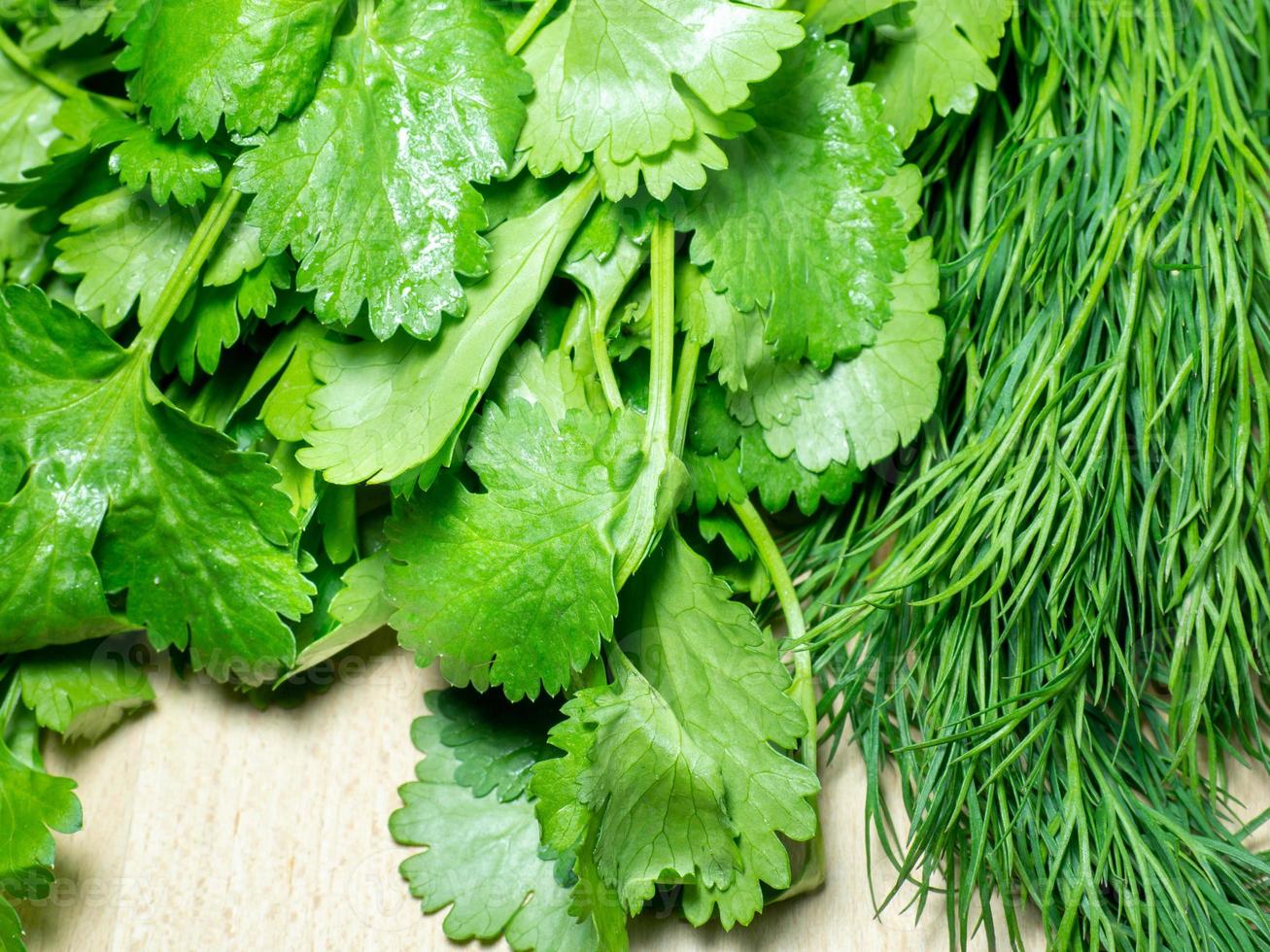 Mix of greens from the garden. Parsley, cilantro, dill on the kitchen table. Cooking. Useful food. Spices for the dish. Salad preparation. photo