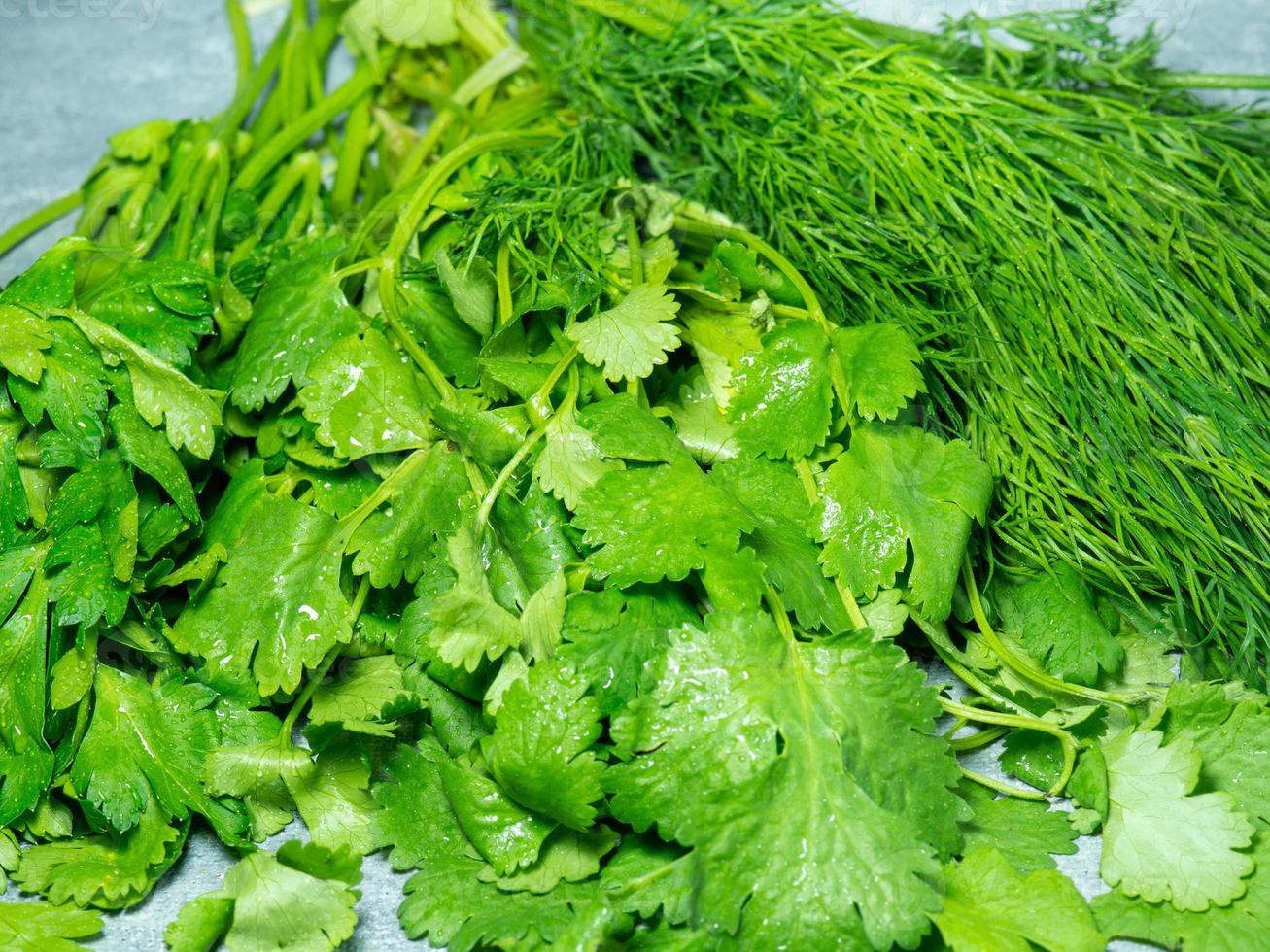 Mix of greens from the garden. Parsley, cilantro, dill on the kitchen table.  Useful food. Spices for the dish. Salad preparation. Green coriander. photo