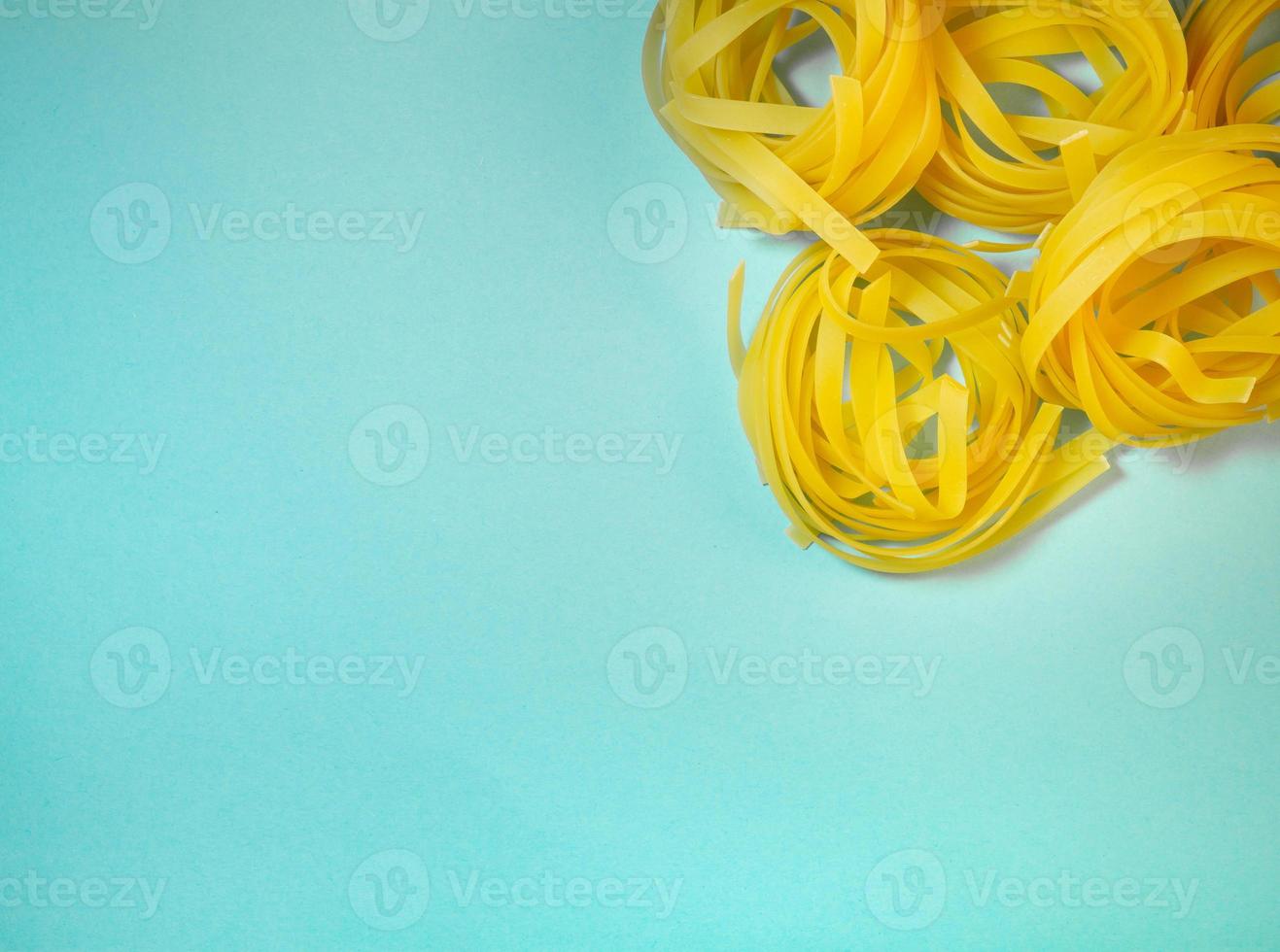 Pasta nests on a blue background. Noodle type. Culinary background. Background from noodles.Pasta on the table. Unprepared product. Cooking. Dough products photo