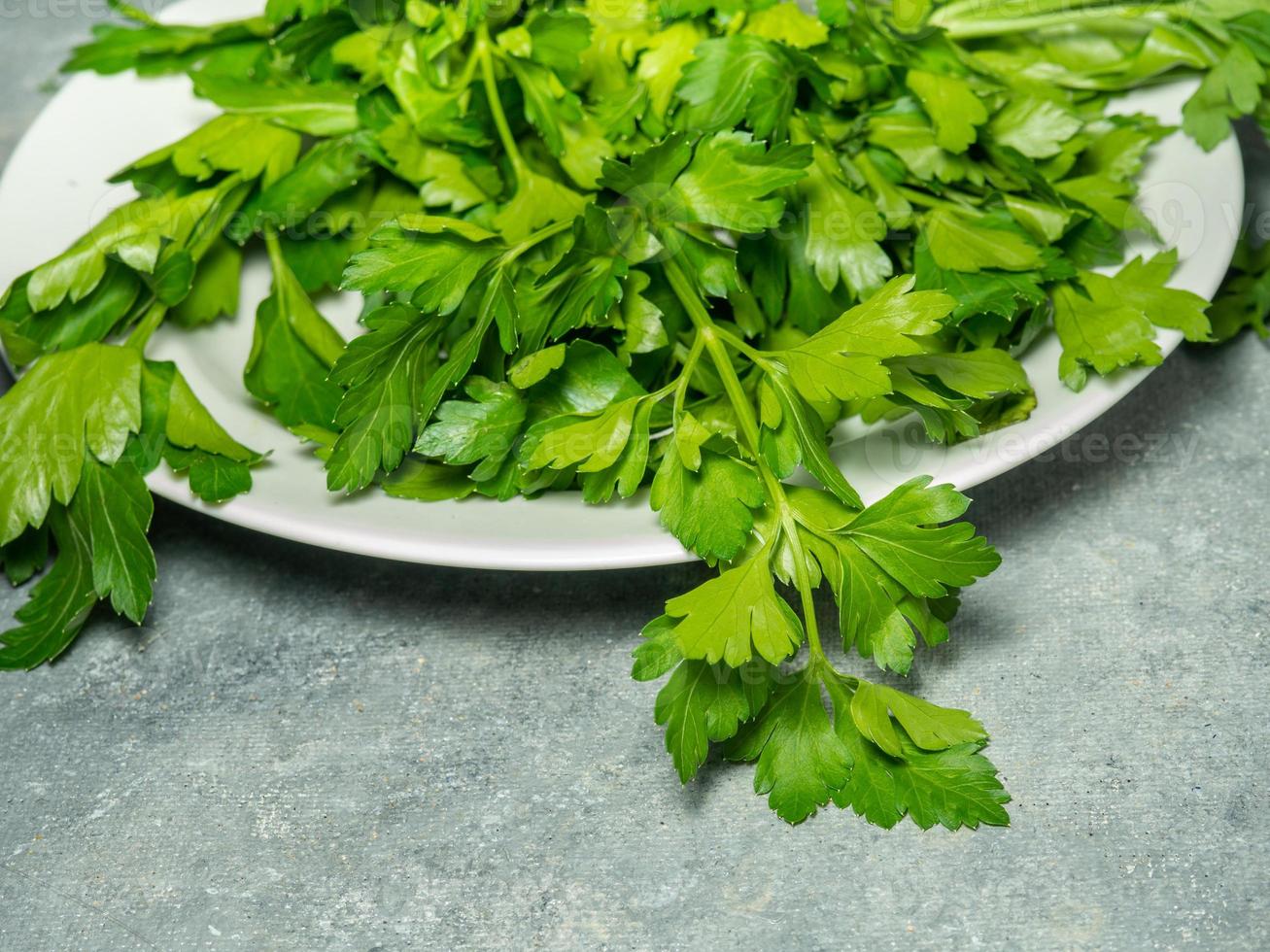 Parsley on the table. Useful product. Greens on a cutting board. Vegetarian lunch ingredient. Lots of parsley stalks. photo