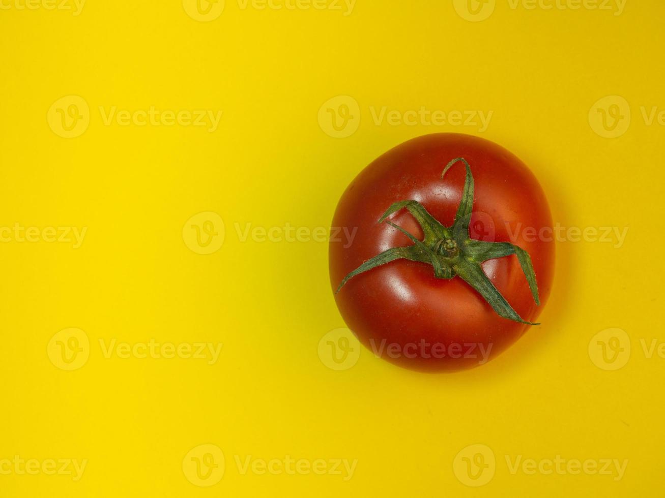 Tomato on colored paper. Greenhouse tomato on a yellow background. Bright vegetable background. photo