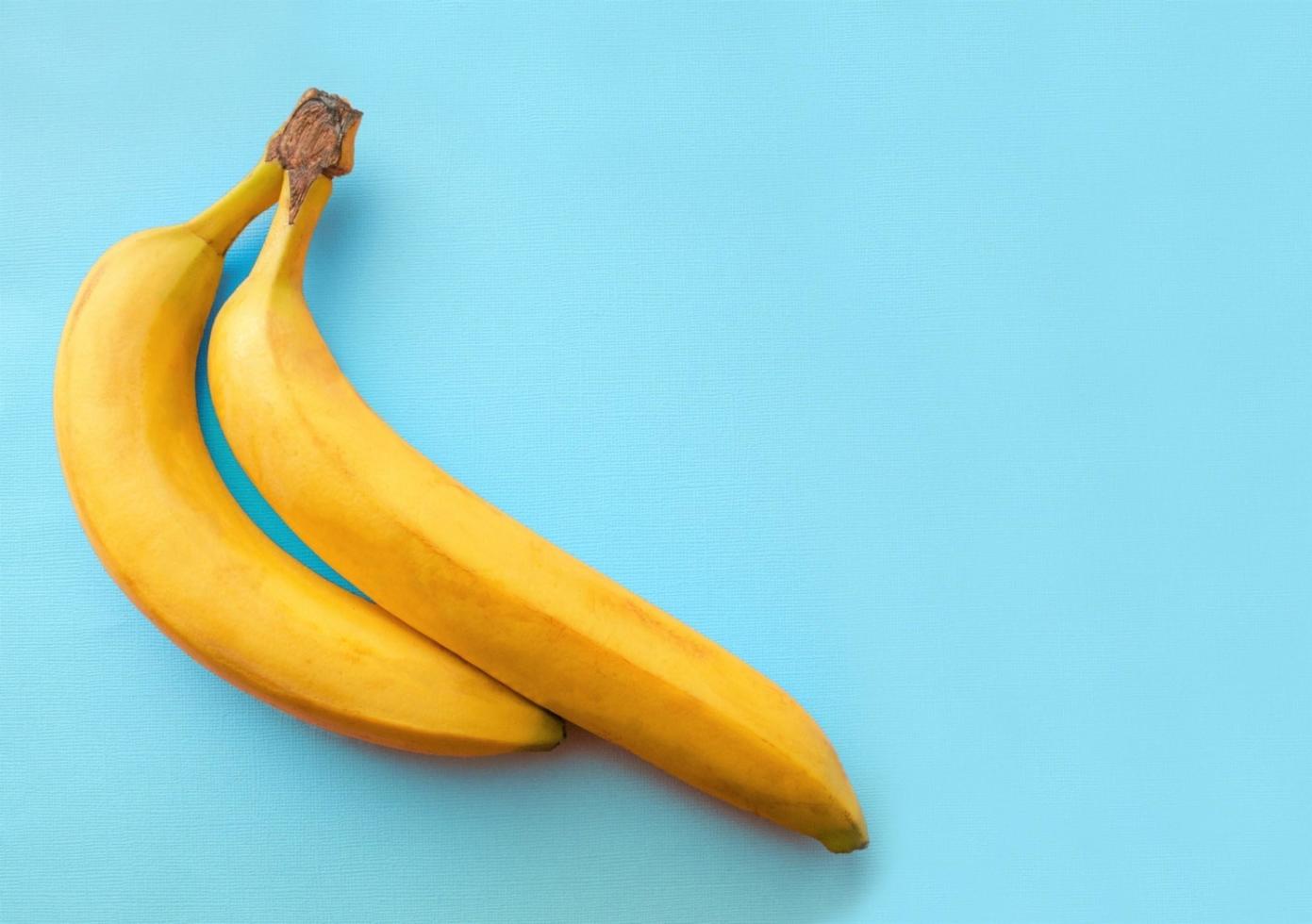 Bananas on a turquoise background. Copy space for text. Two bananas. Couple of bananas. Light blue background. photo