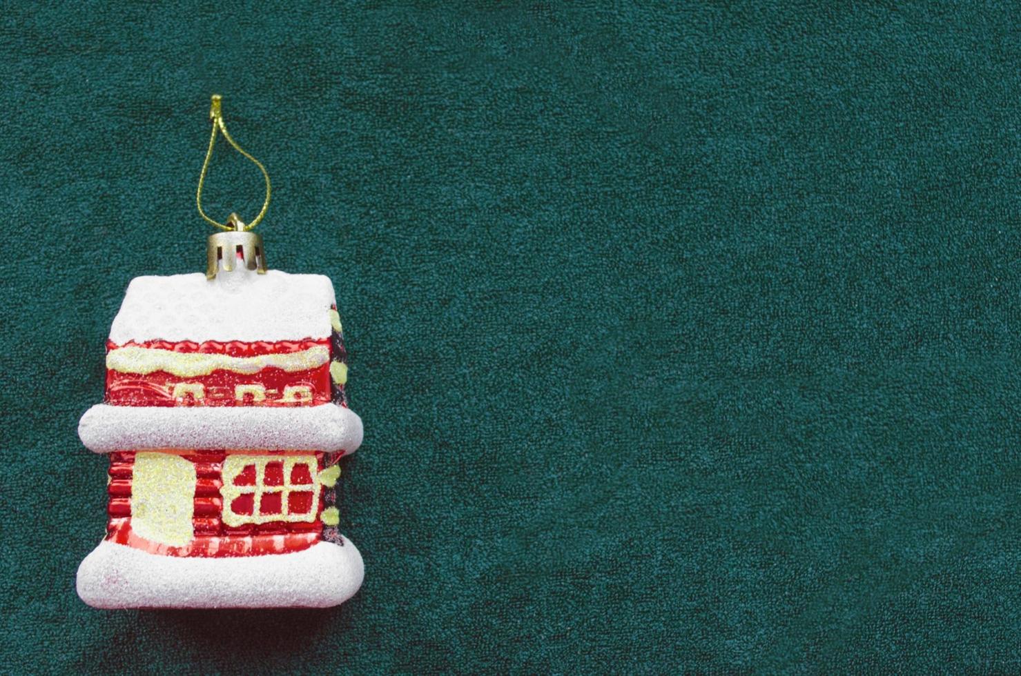 casa de juguete de árbol de navidad sobre fondo verde. copie el espacio para el texto. comprar una casa en el nuevo año. foto