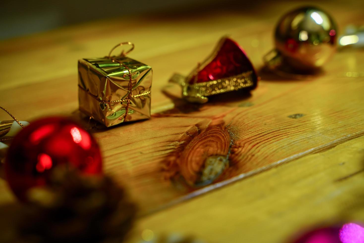 New Year and Christmas gift themed decorations on wooden background, consisting of a golden gift box.  shiny colored balls  Dried pine cones and small bells  free space for design photo