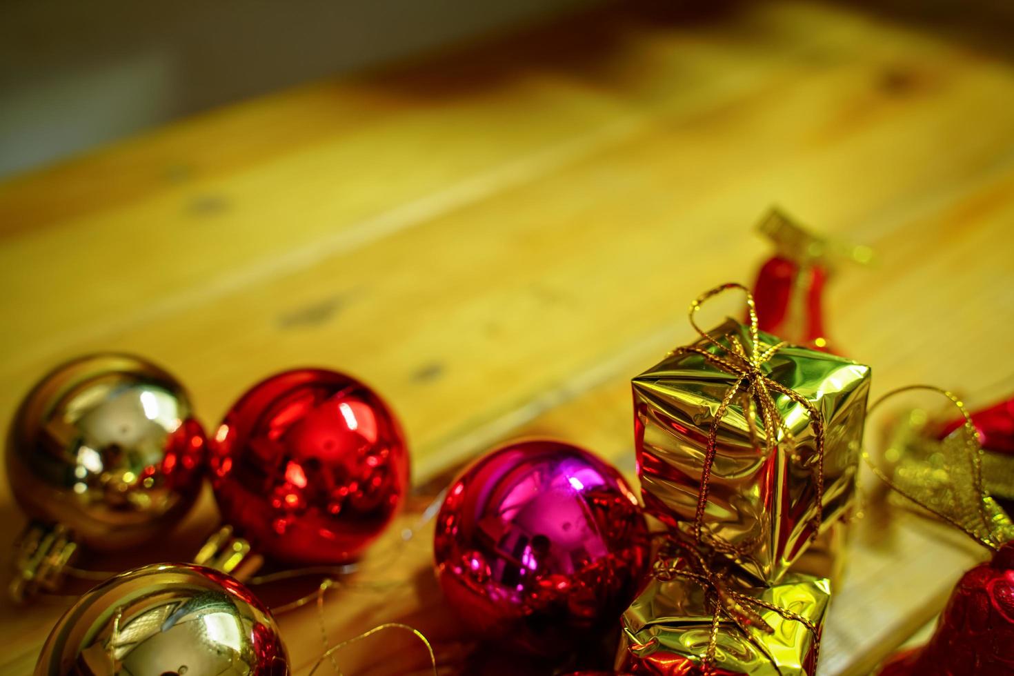 New Year and Christmas gift themed decorations on wooden background, consisting of a golden gift box.  shiny colored balls  Dried pine cones and small bells  free space for design photo