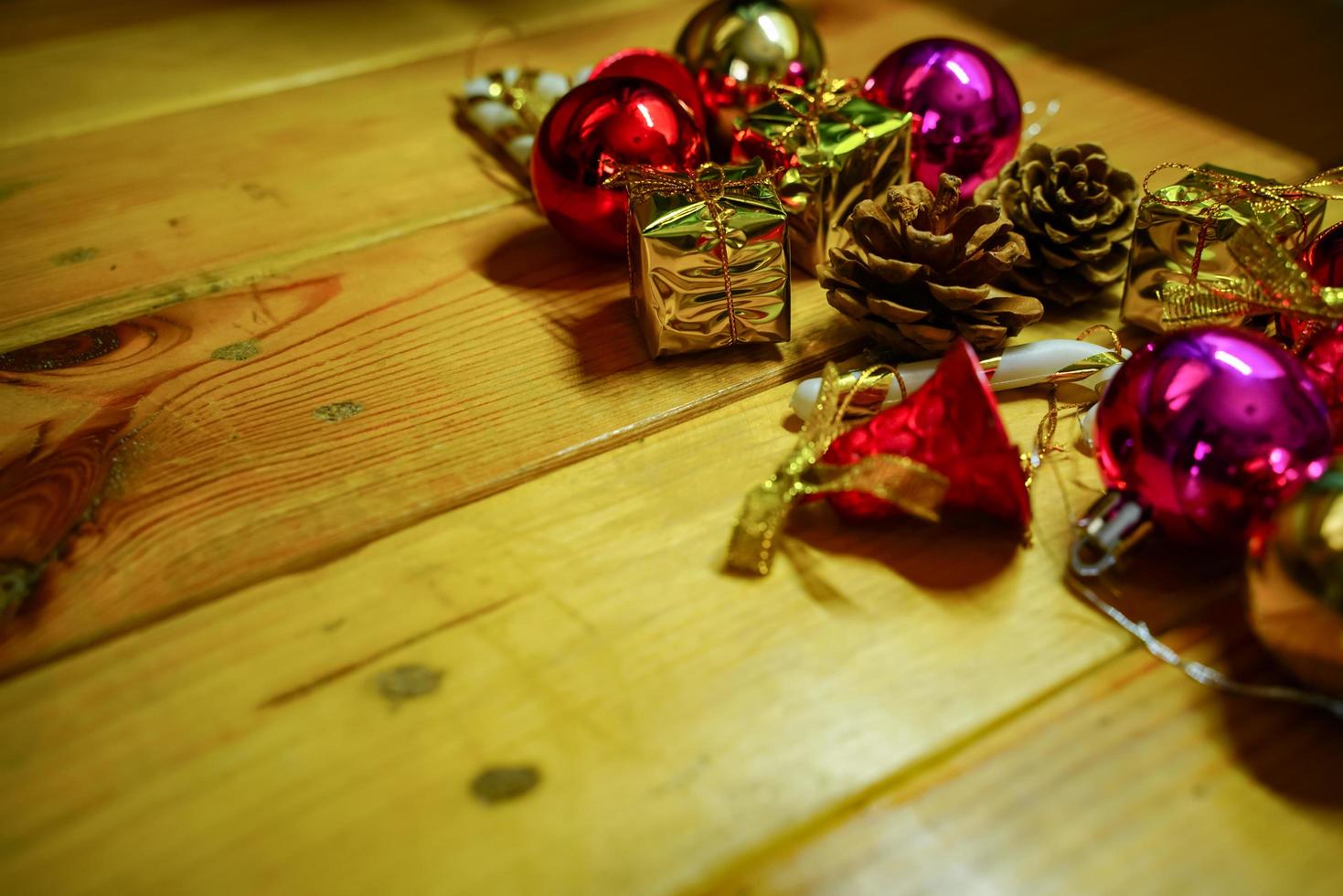 New Year and Christmas gift themed decorations on wooden background, consisting of a golden gift box.  shiny colored balls  Dried pine cones and small bells  free space for design photo