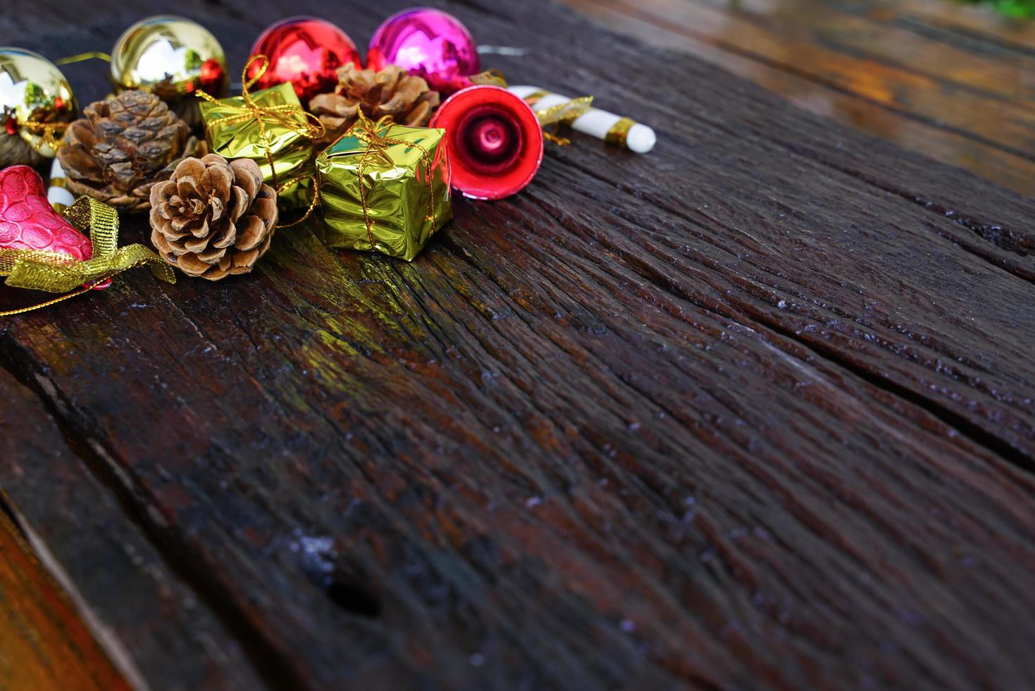 New Year and Christmas gift themed decorations on wooden background, consisting of a golden gift box.  shiny colored balls  Dried pine cones and small bells  free space for design photo